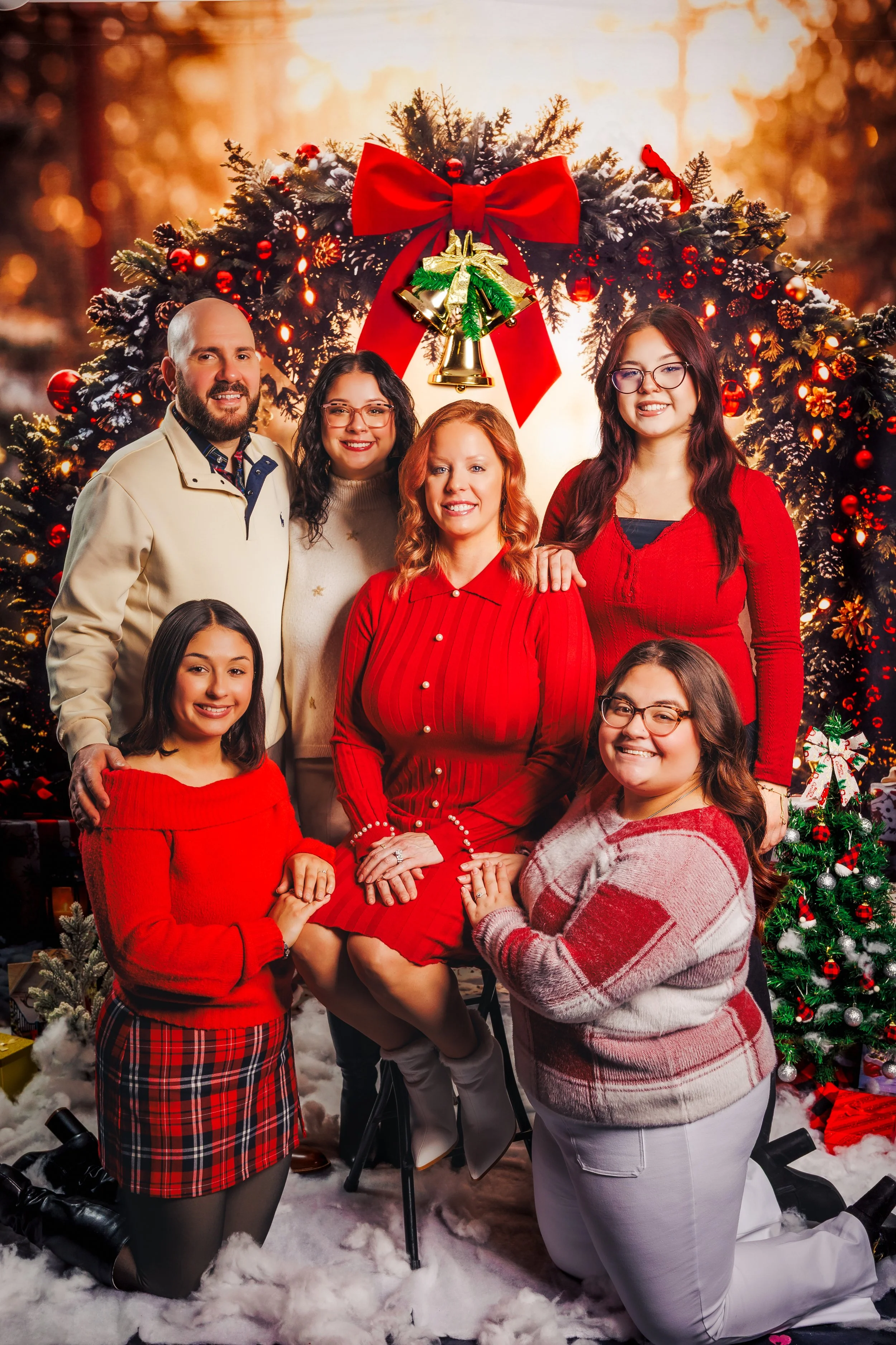 Family gathered for a Christmas photo, with decorated Christmas tree and festive decorations in the background.