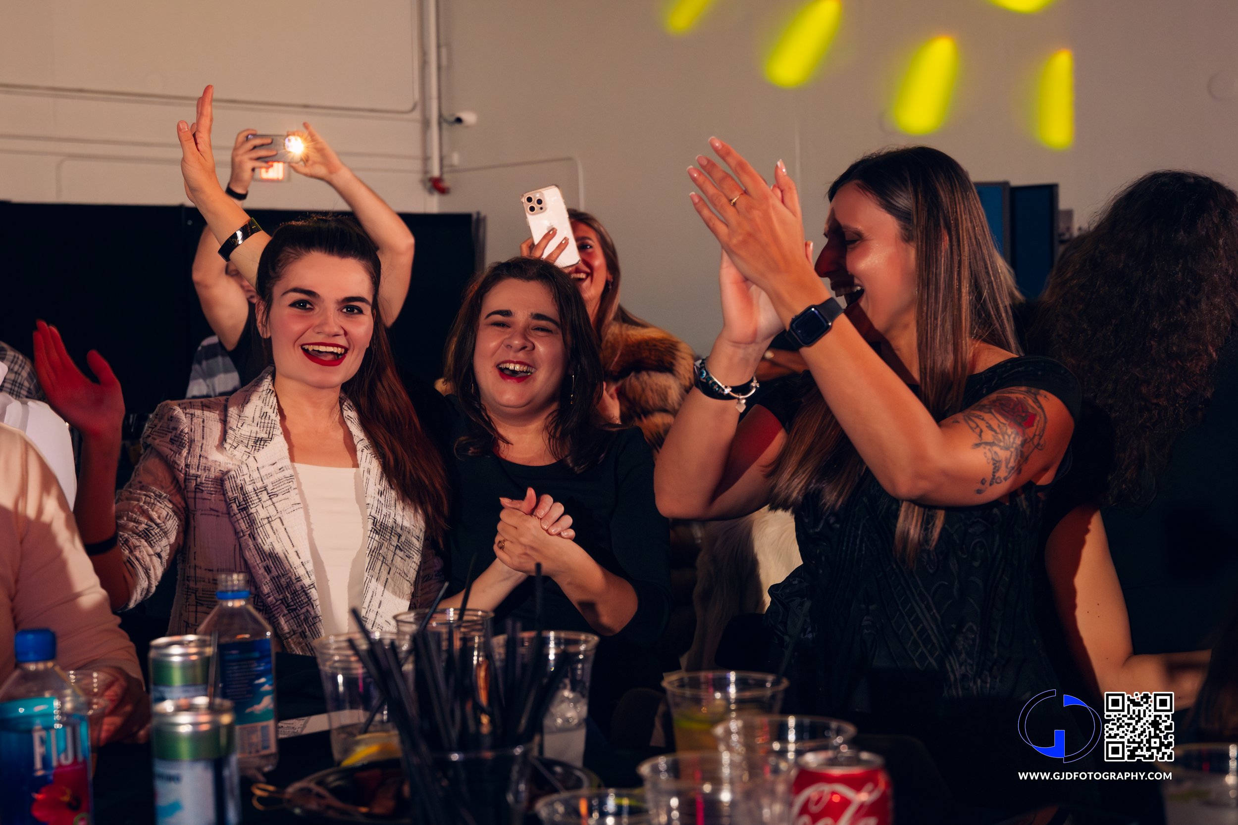 People celebrating, smiling, clapping, and taking photos at a party