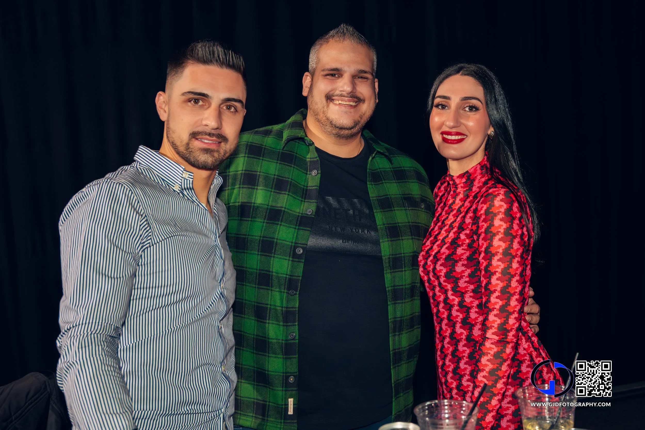 Three adults friends posing together indoors with drinks at a social gathering