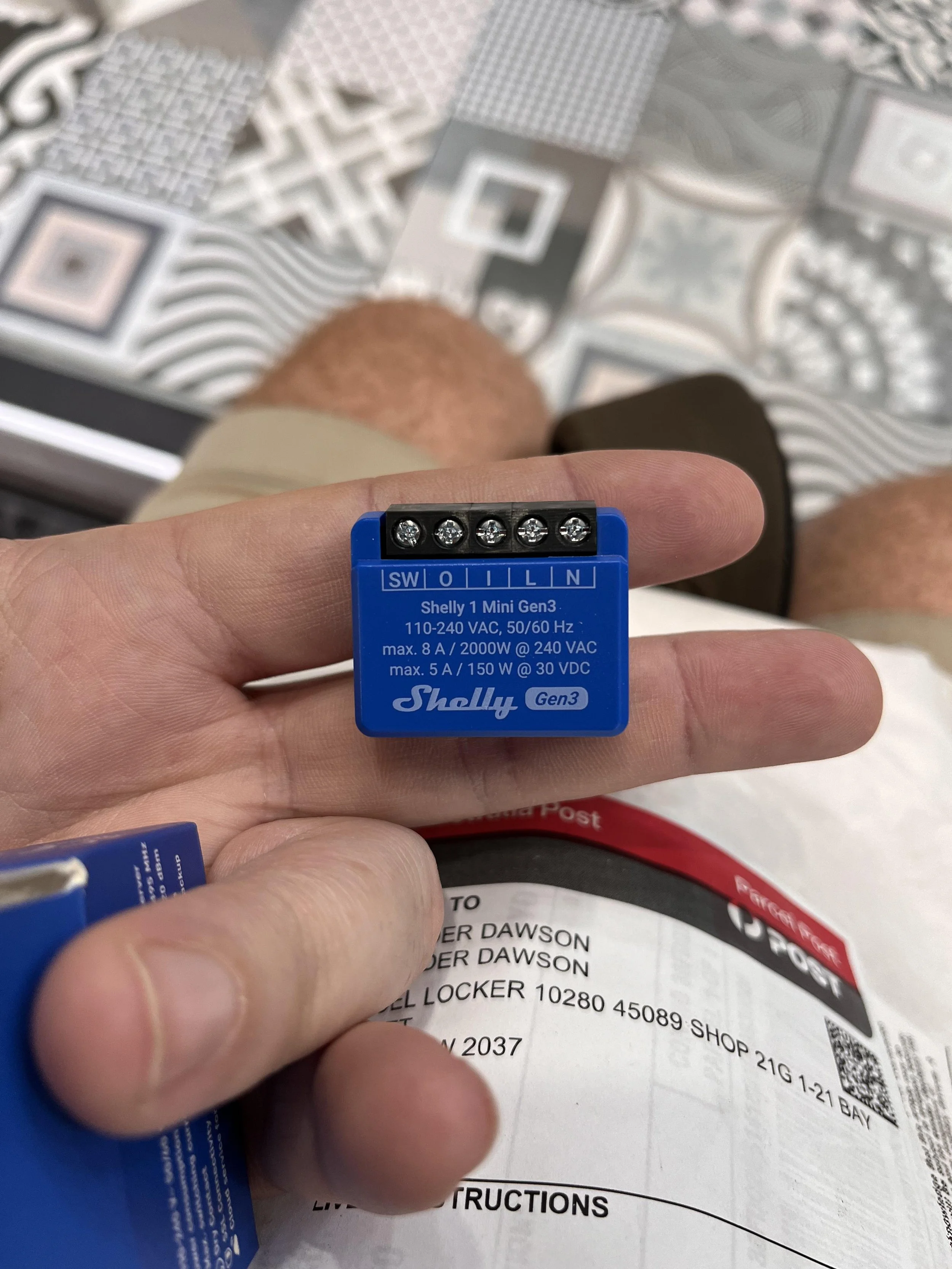 Person holding a Shelly 1 Mini Gen3 device above a parcel.