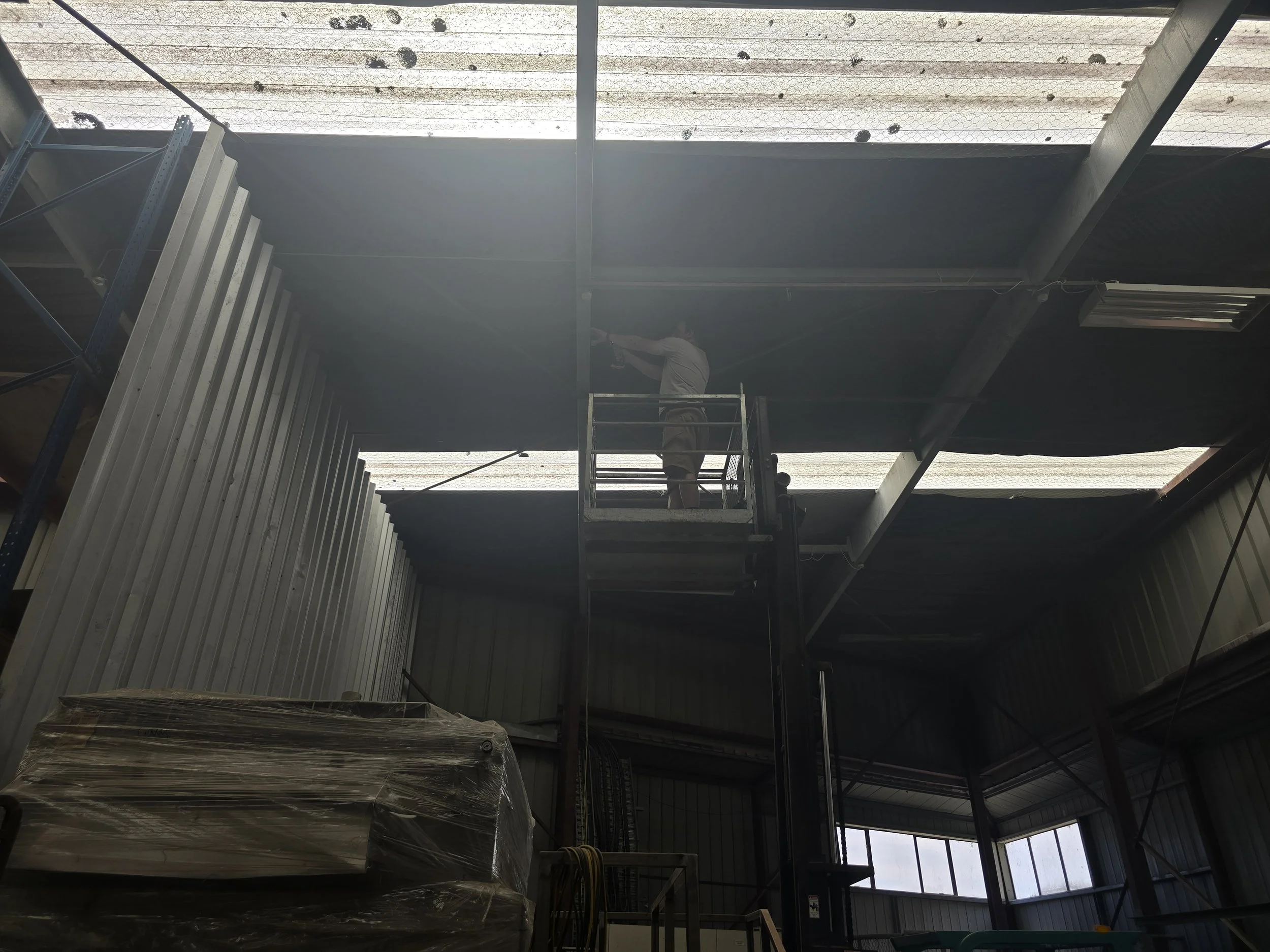 Person working on warehouse ceiling from scaffolding