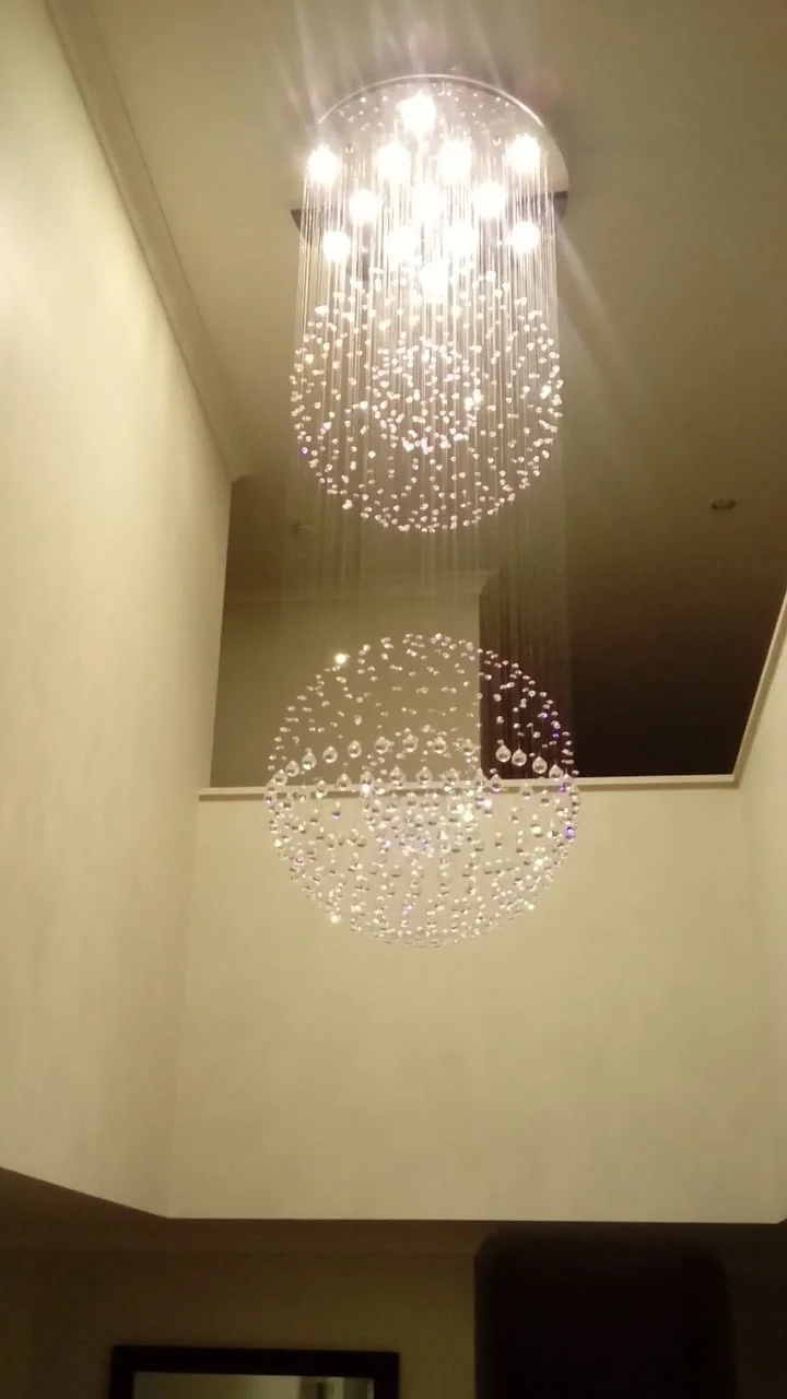 Modern crystal chandelier with spherical design, hanging in a hallway.