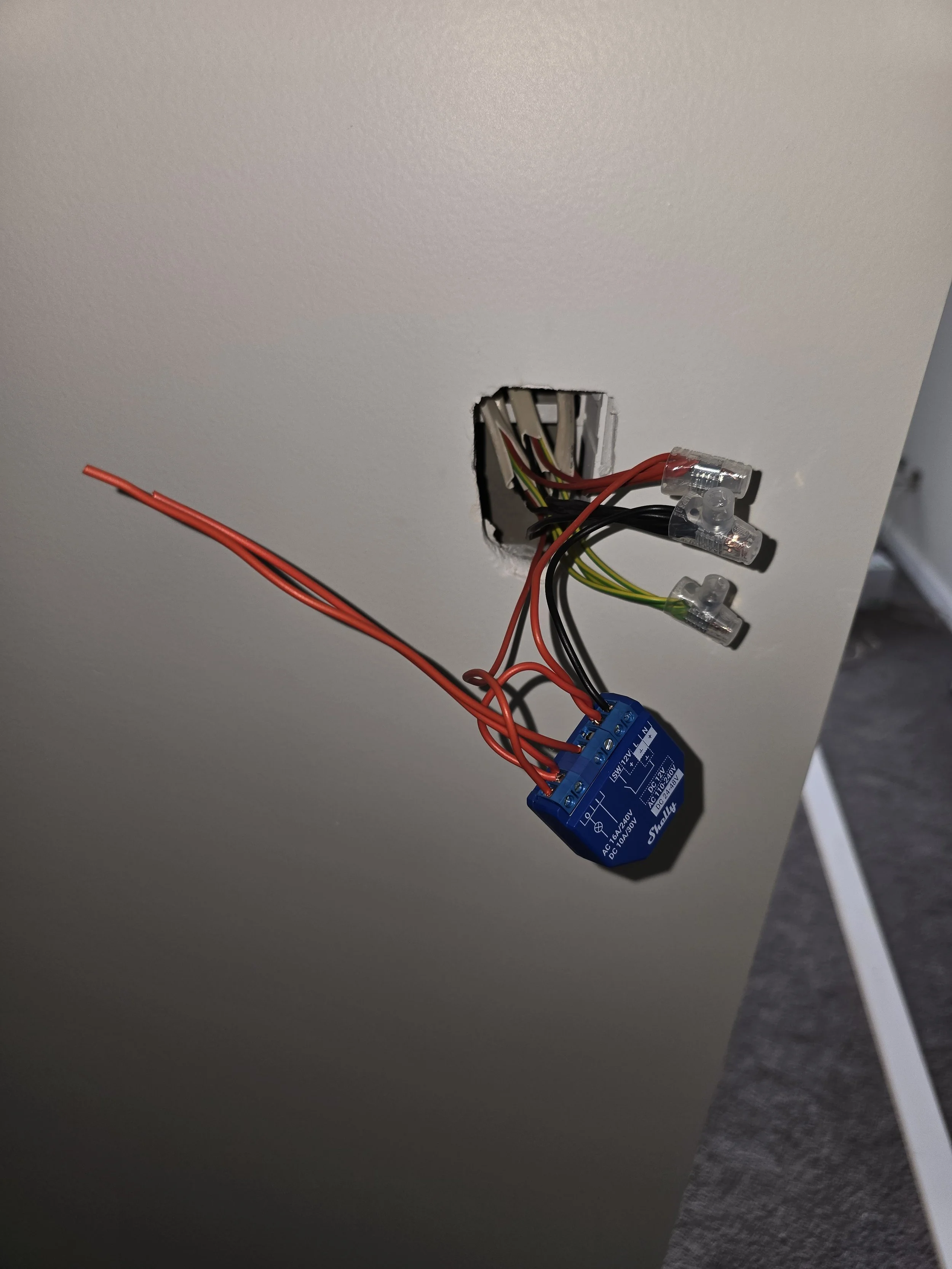 Electrical wiring protruding from a wall with a blue relay switch and connected wires.