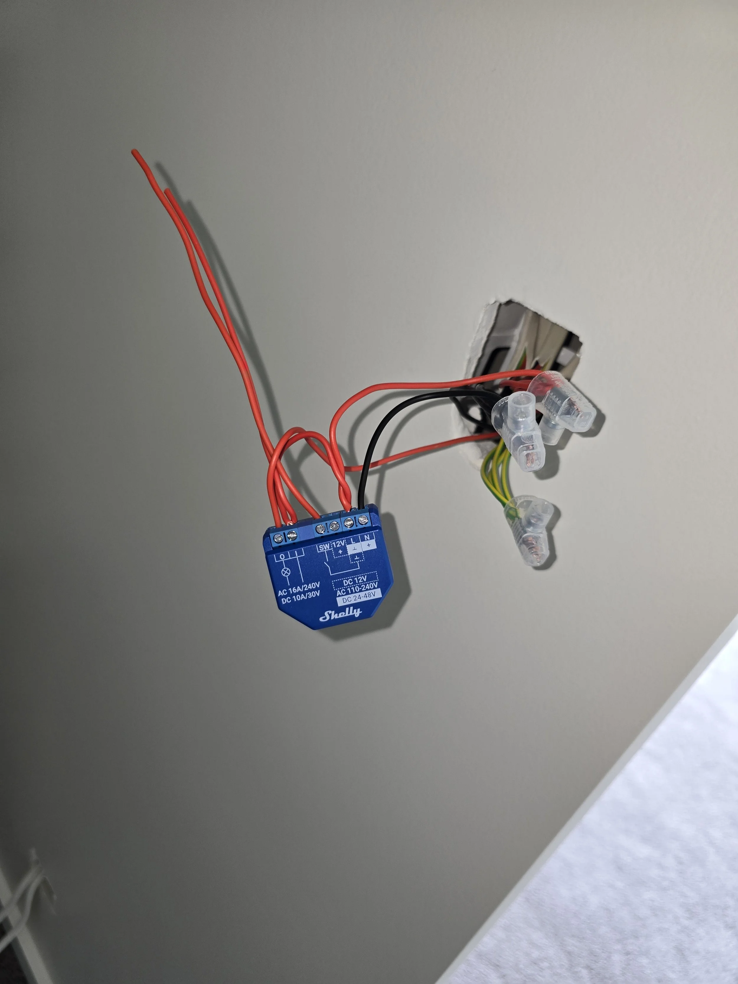 A wall-mounted smart relay module with exposed wiring and connectors.