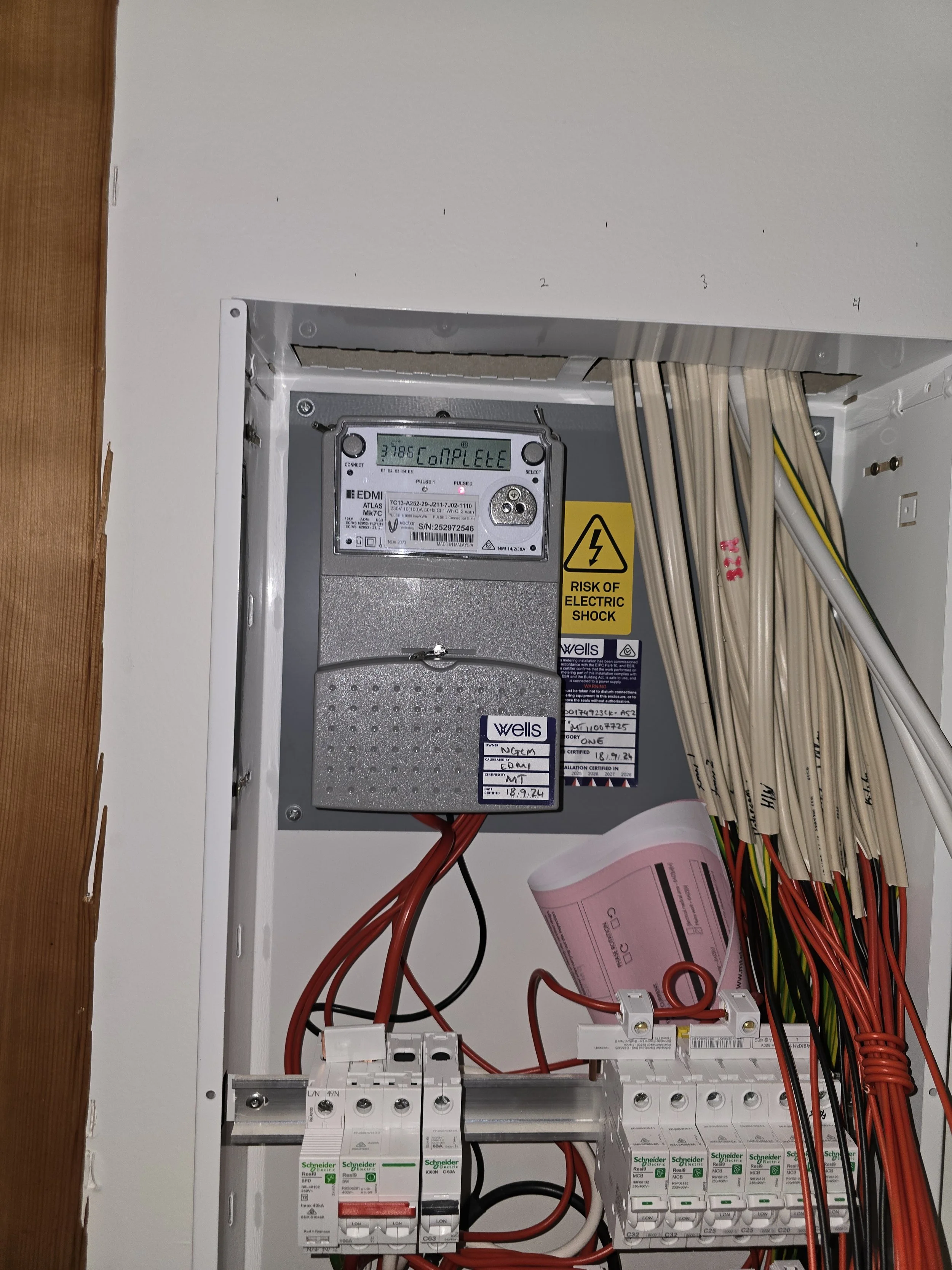 Electrical panel with wires, circuit breakers, and a risk of electric shock warning label.
