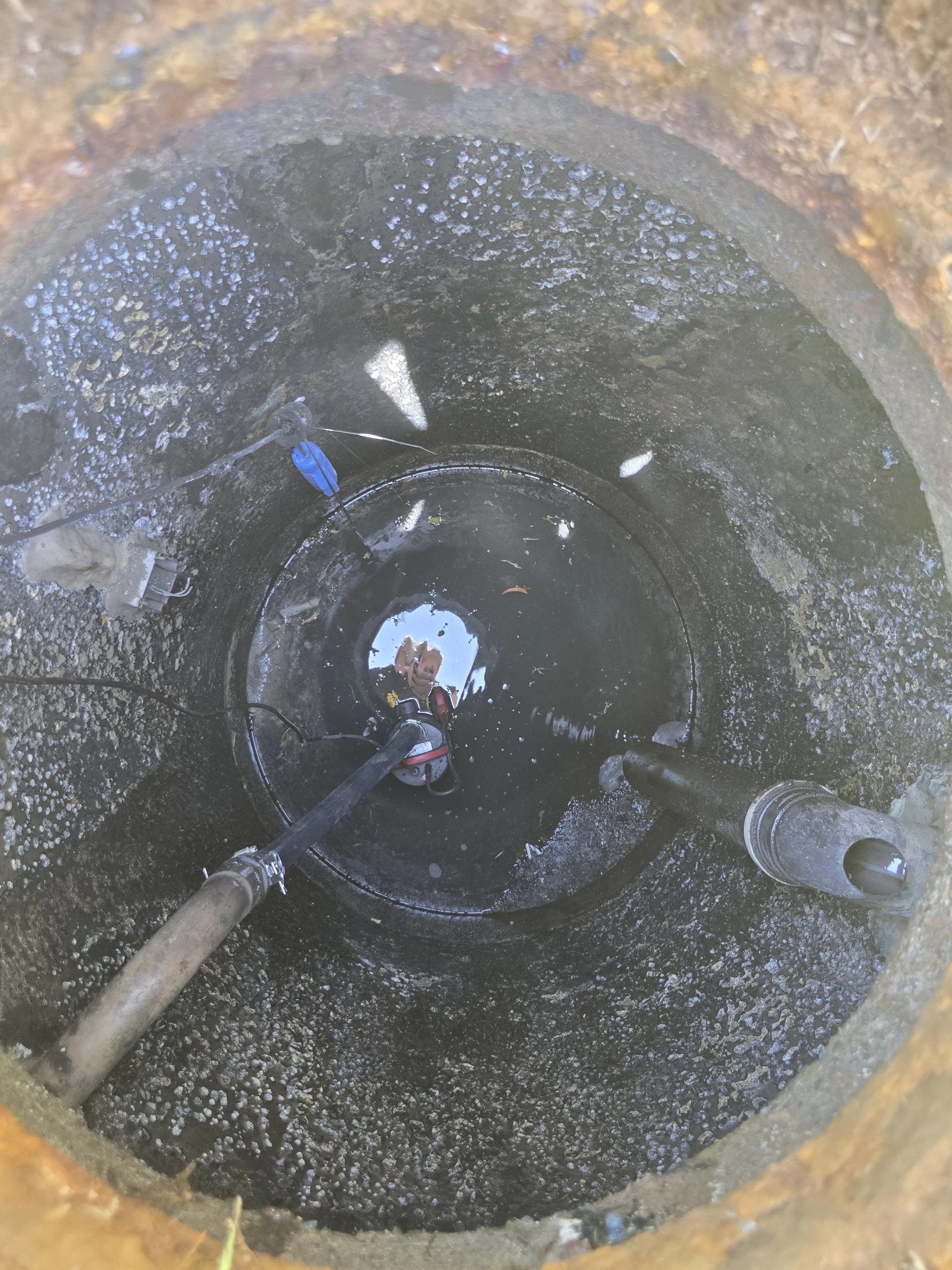 Inside view of a manhole showing pipes and water at the bottom