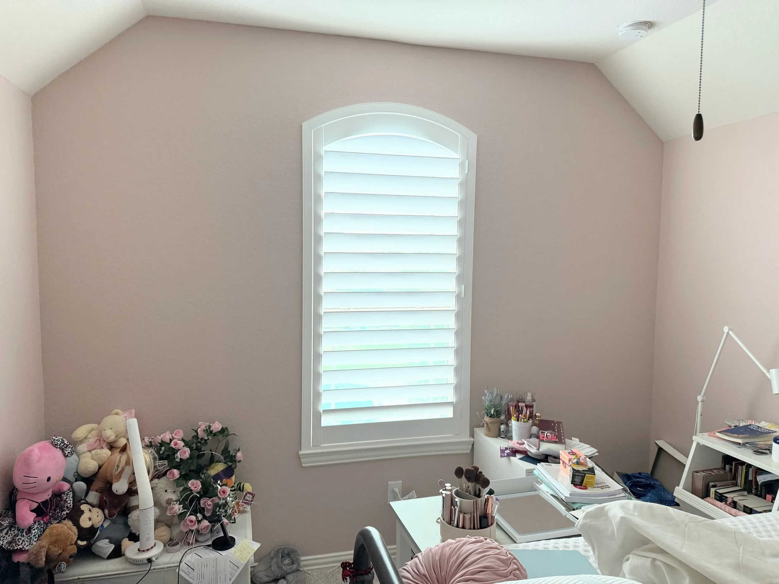 An eyebrow-arch white plantation shutter with 4.5-inch louvers, hidden rear tilt, and a Modern frame in a bedroom.