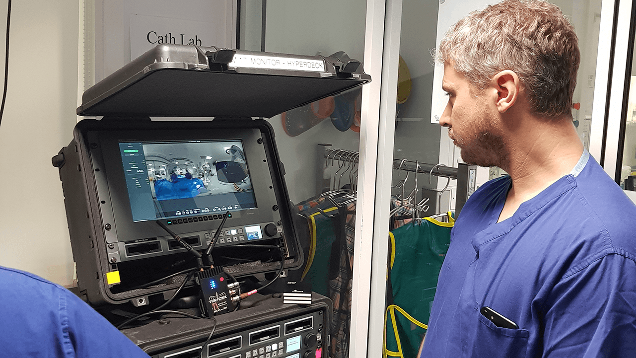Safe from the harmful radiation from the constant X-rays, Andrew watches the live angioplasty from the live stitch on the wireless monitor.