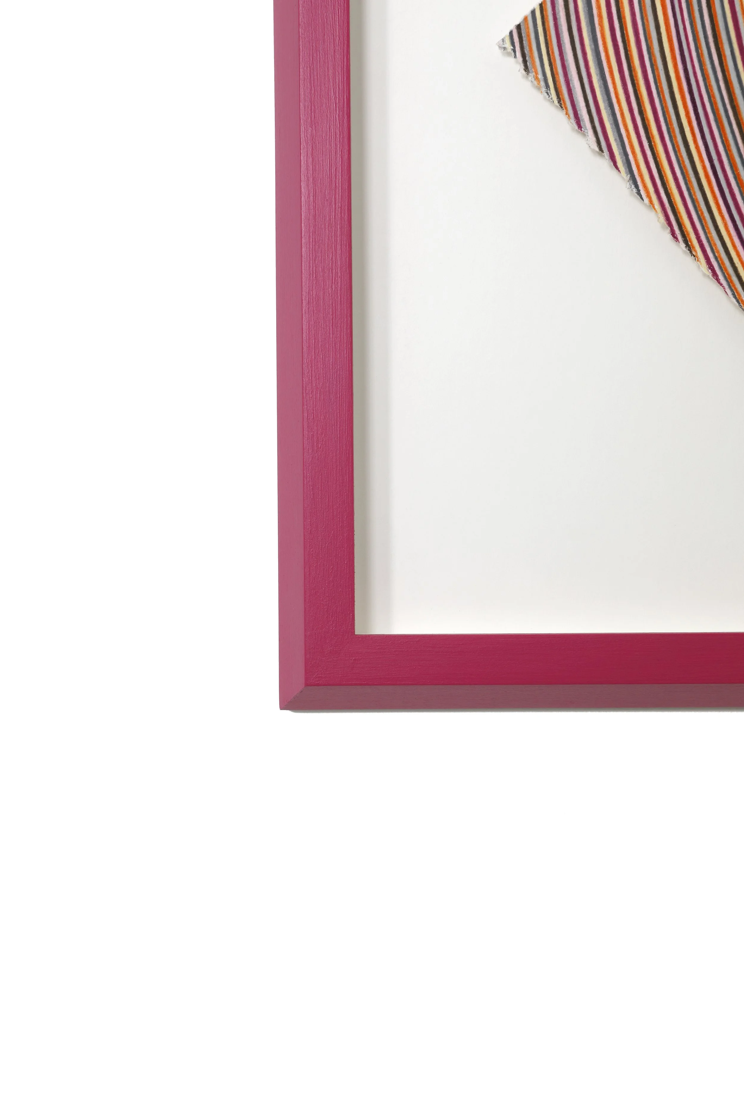 Close-up of a pink picture frame with a corner visible, with part of a striped fabric in the top right corner.