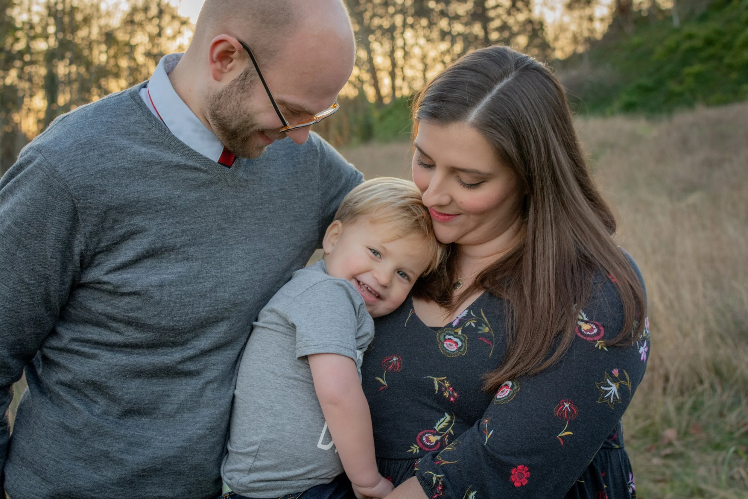 Family photographed in Tacoma, WA.  Little boy being held by his parents during golden hour session