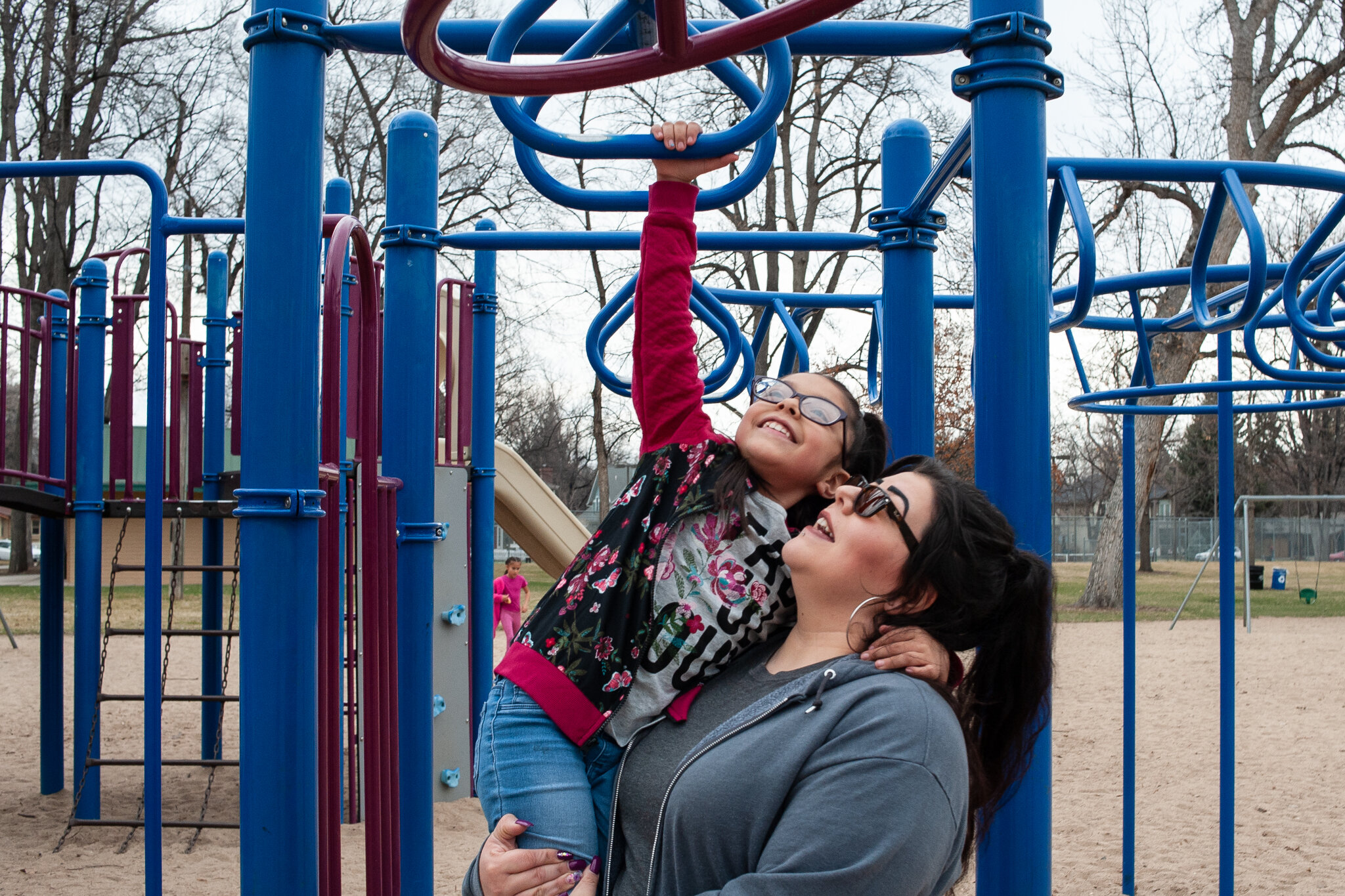  Fylesha Martinez helps her daughter Monica Martinez, 7, reach the monkey bars at City Park in Fort Collins on Wednesday, March 18, 2020.  “We’re being more cautious with hand sanitizer, but we’re not going to live in fear,” Martinez said. (Valerie M