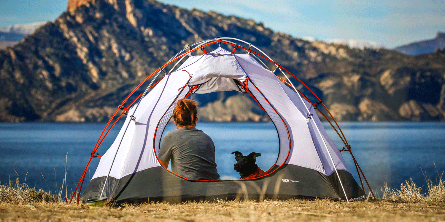 Women camping in the mountains by a river with her dog - who would use Shower in a Can instead of wet wipes