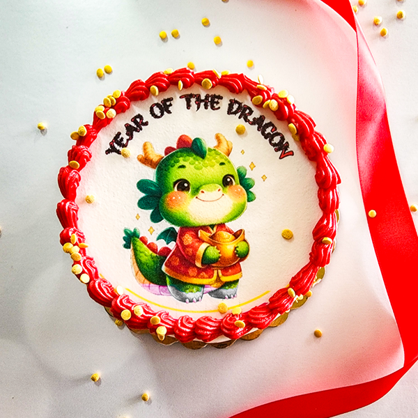 Decorated cake with a cartoon dragon holding a toy, surrounded by red and yellow sprinkles, with the words 'Year of the Dragon' written on top.