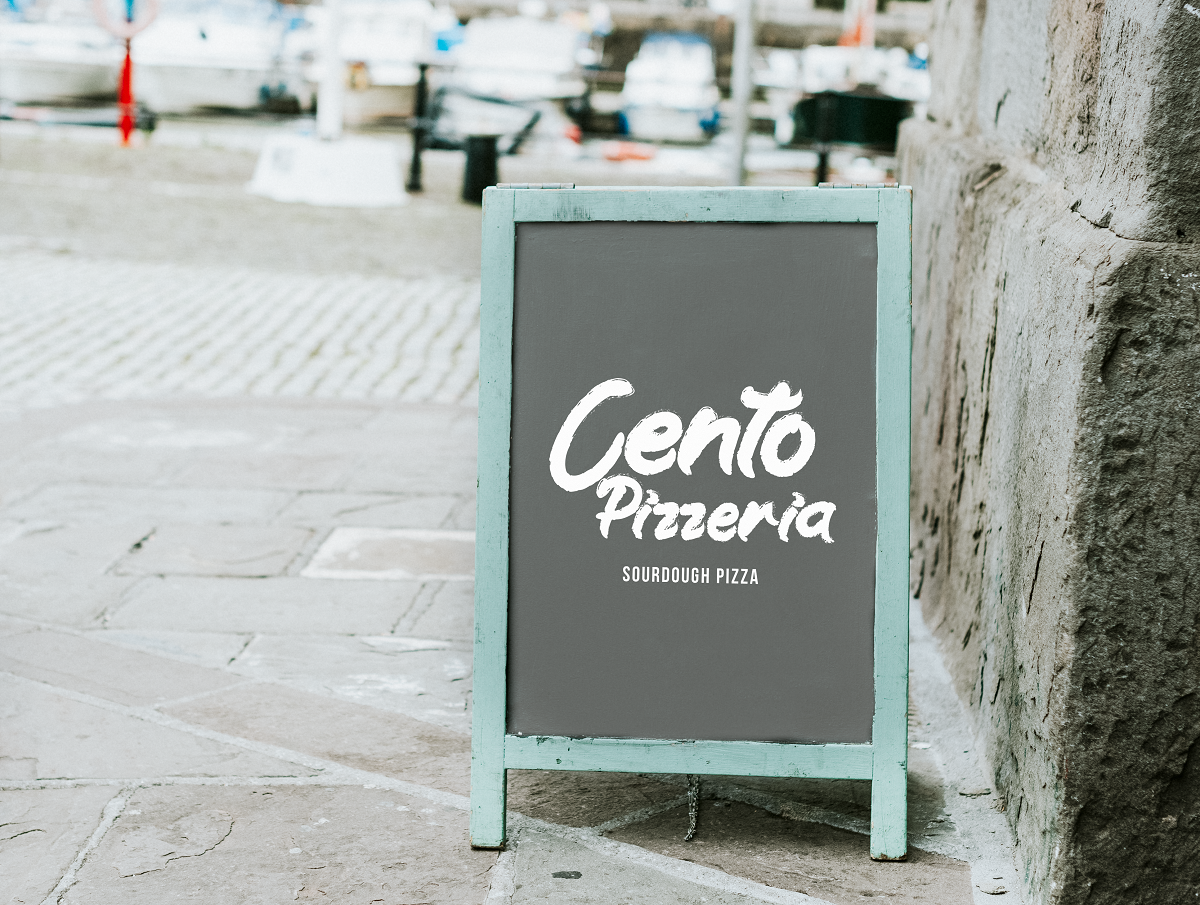Cento Pizzeria logo on a chalkboard A-frame sign on the street.