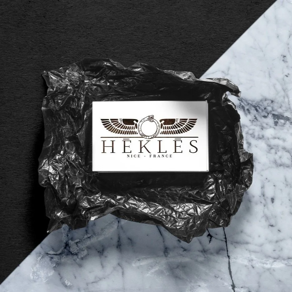 Business card with the HÉKLÈS logo on black stone.