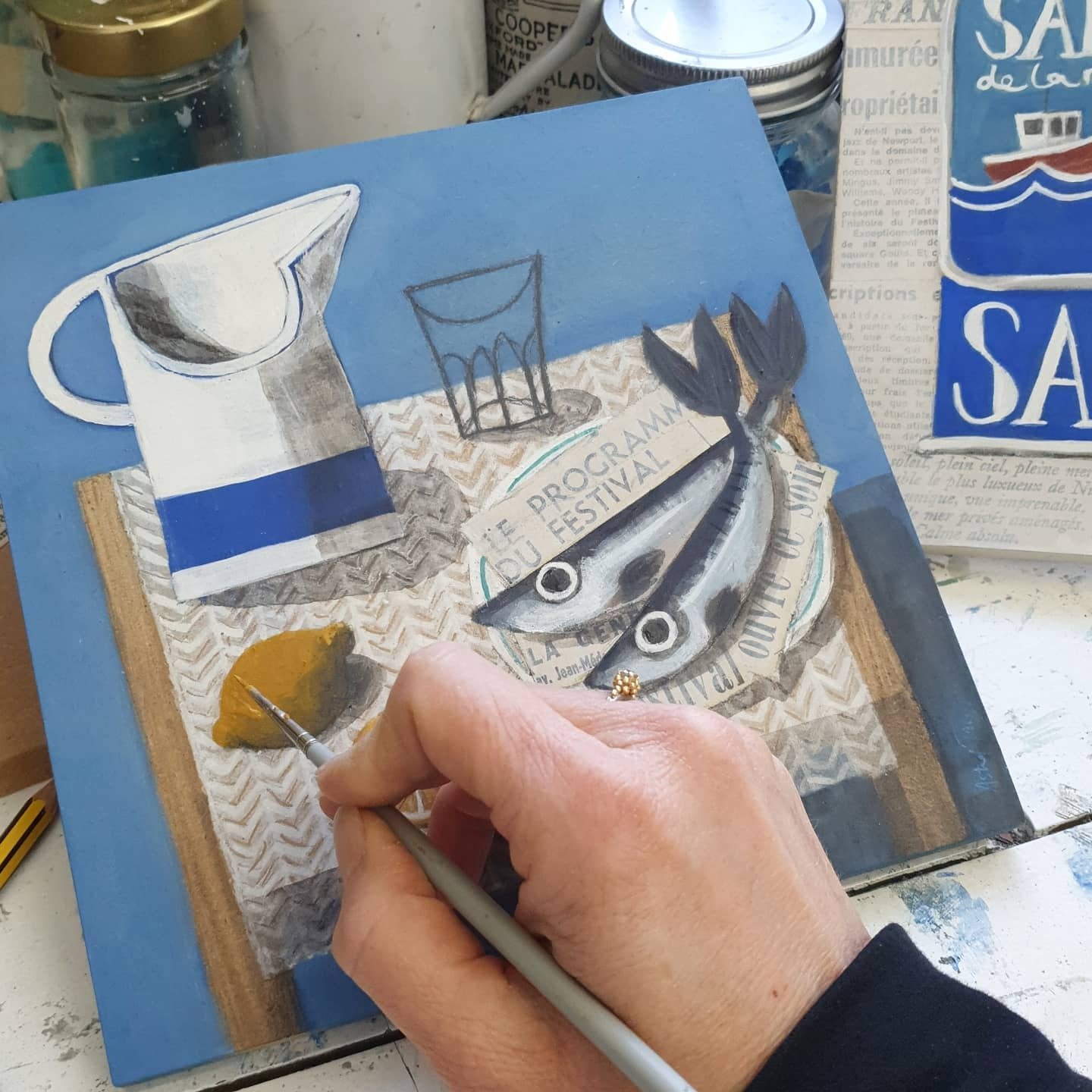 Close-up of a fish still life painting in progress with hand-mixed pigments and collage.