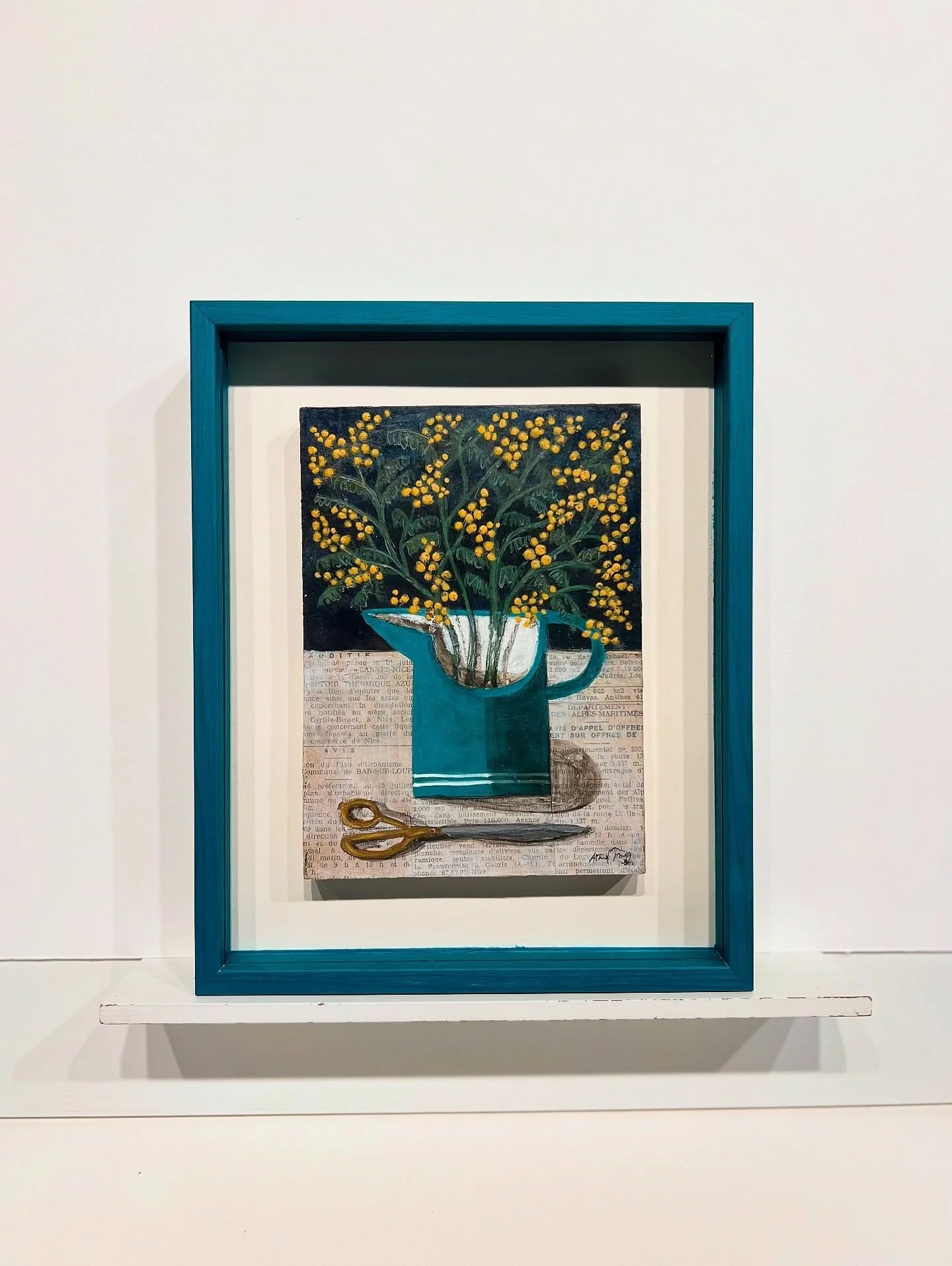 Framed mixed media flower painting with collage and pigment, displayed on a white gallery shelf.