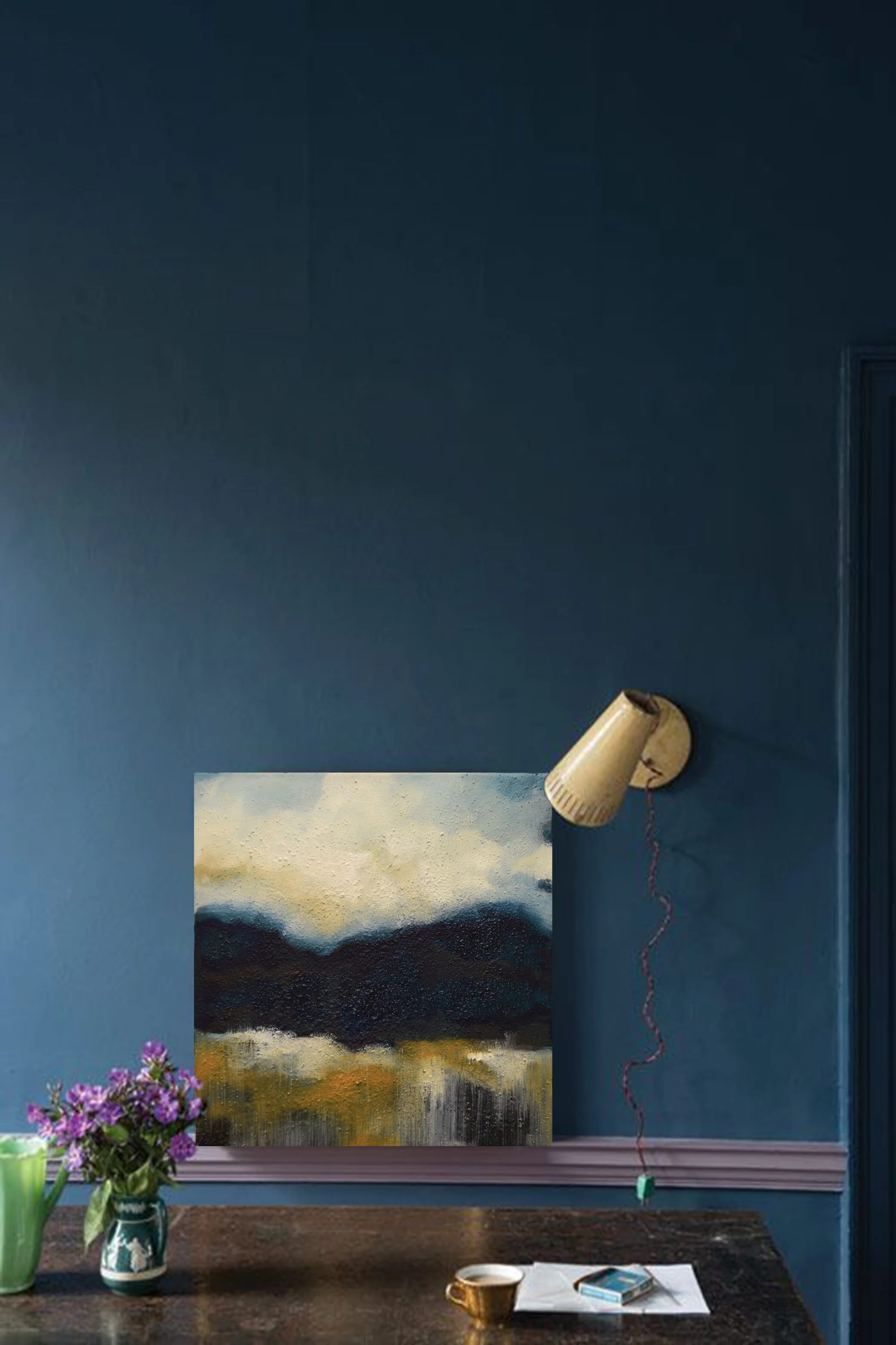 A small landscape painting by Tracy Sweeney hanging on a blue wall.