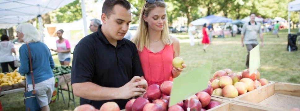 Man and woman at farmers market shopping apples
