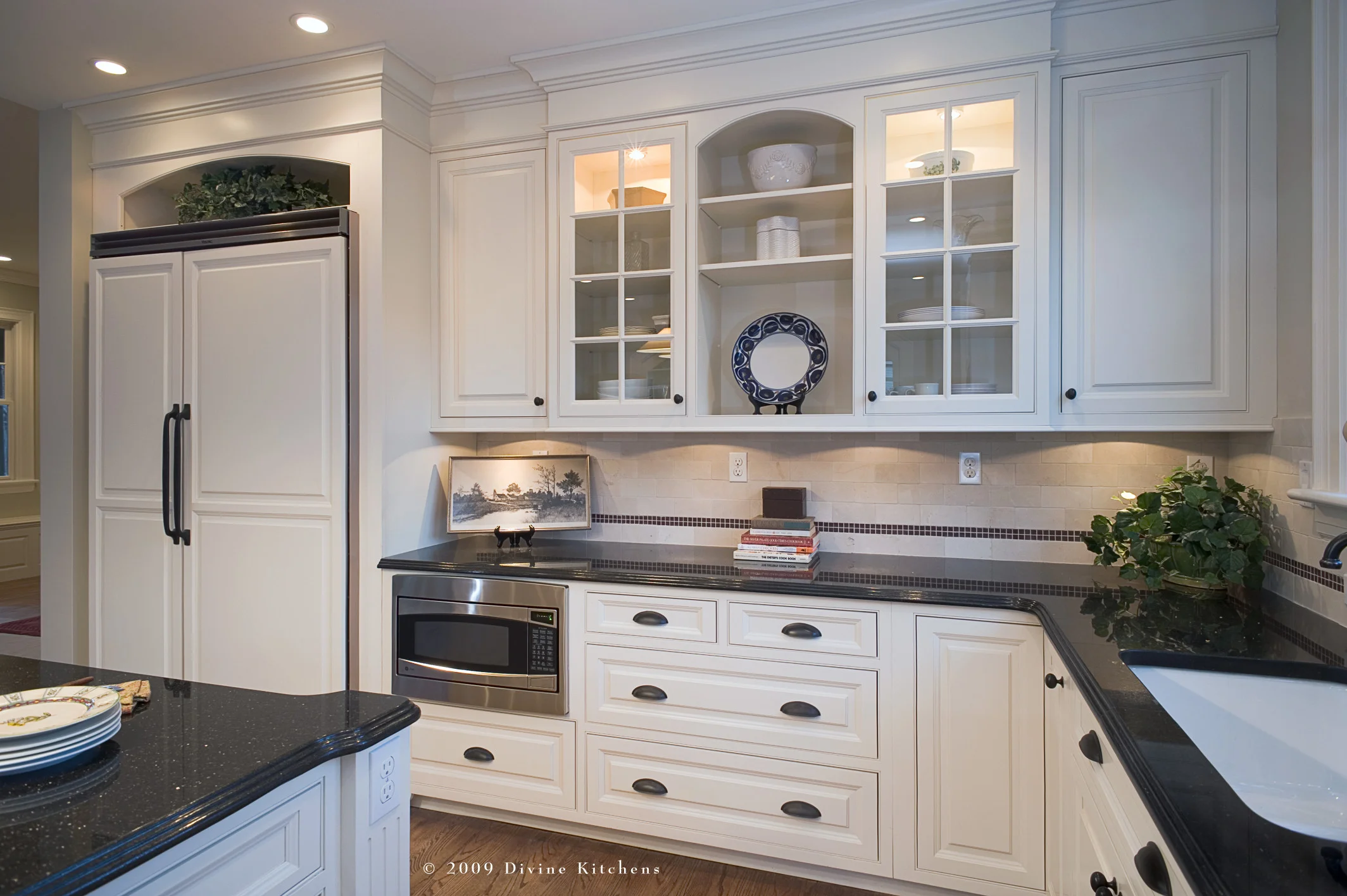 traditional kitchen with white shaker cabinets and dark granite countertops. Wrought iron chandelier, and oil rubbed bronze faucets