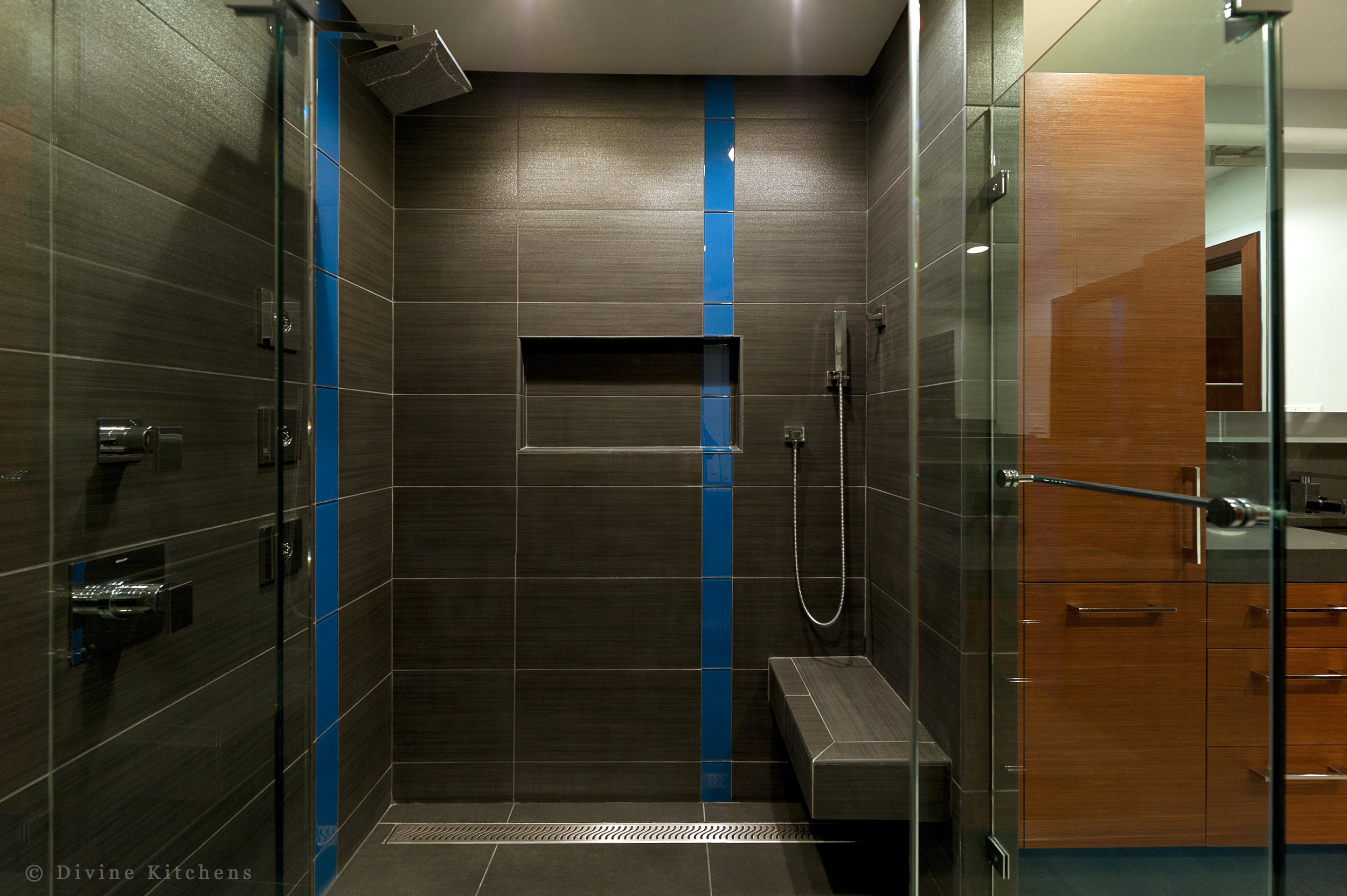 Modern bathroom with cherry veneer cabinets and slate tile shower and bathroom floors. Granite countertop and sink basin. Blue tile accents.