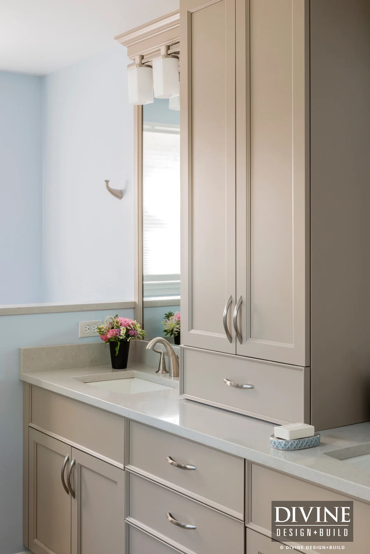 Transitional bathroom with baby blue wall paint, off white vanity cabinets and brushed nickel accessories. Mosaic tile niche with stone tile surround.