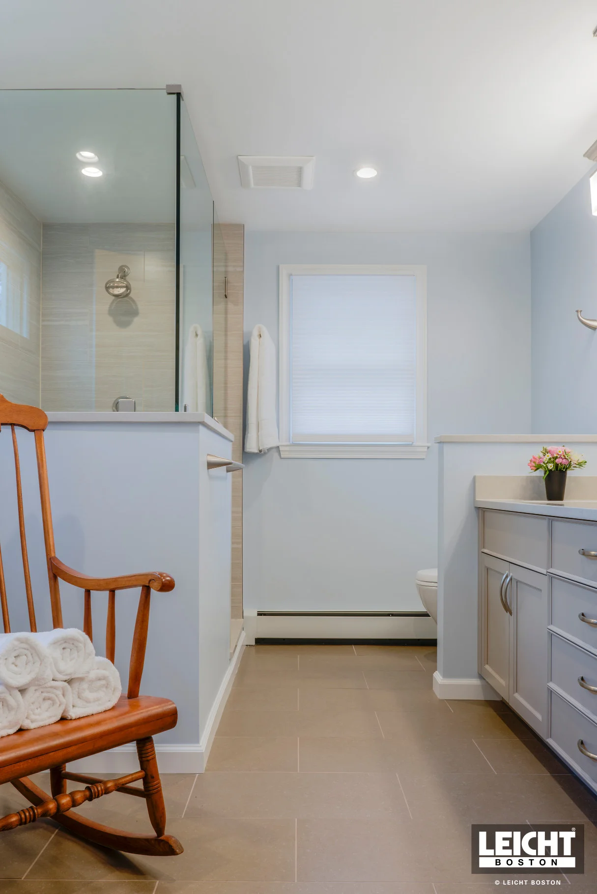 Transitional bathroom with baby blue wall paint, off white vanity cabinets and brushed nickel accessories. Mosaic tile niche with stone tile surround.