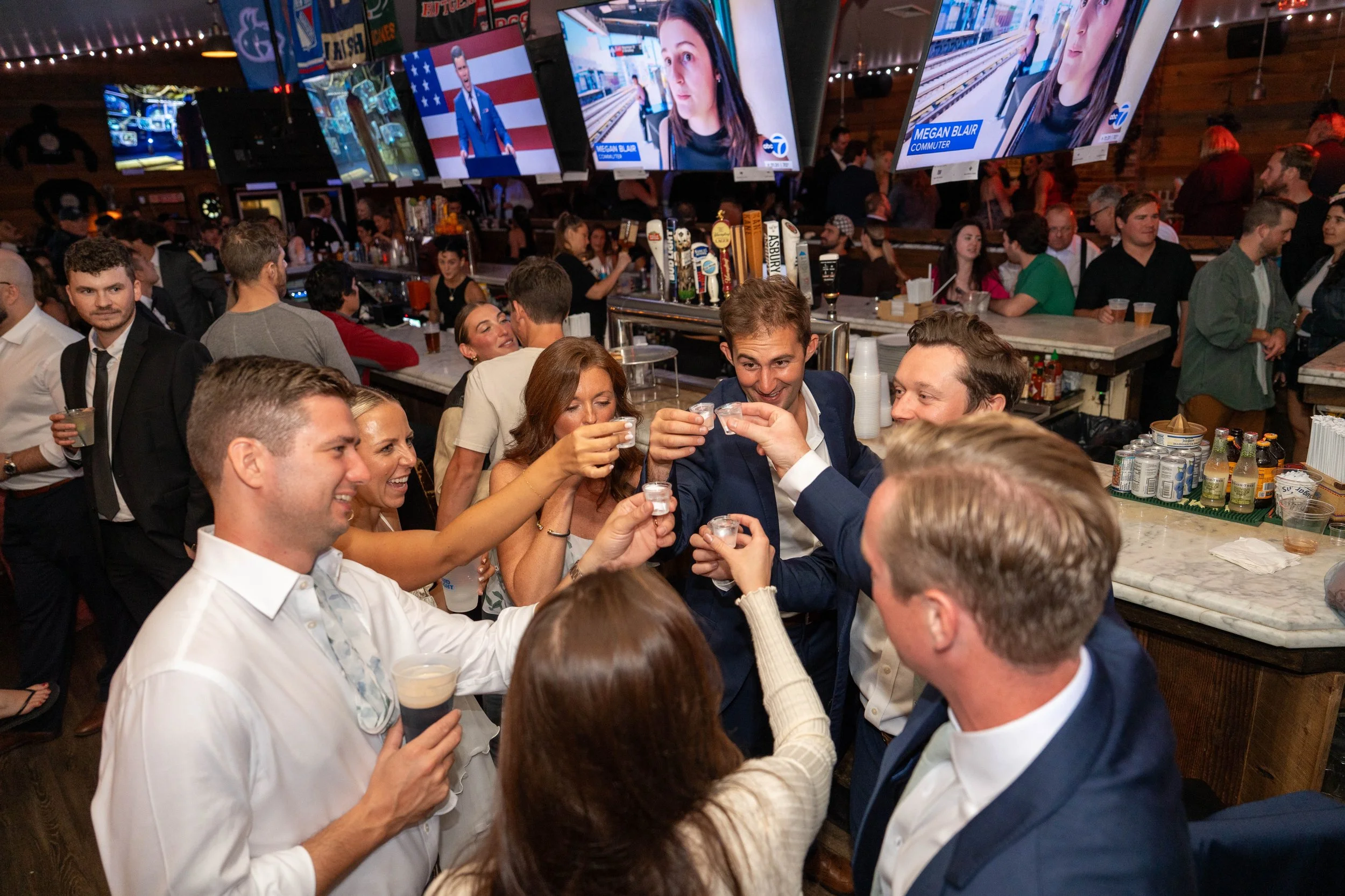 People in a bar raising shot glasses and toasting at a celebration party.