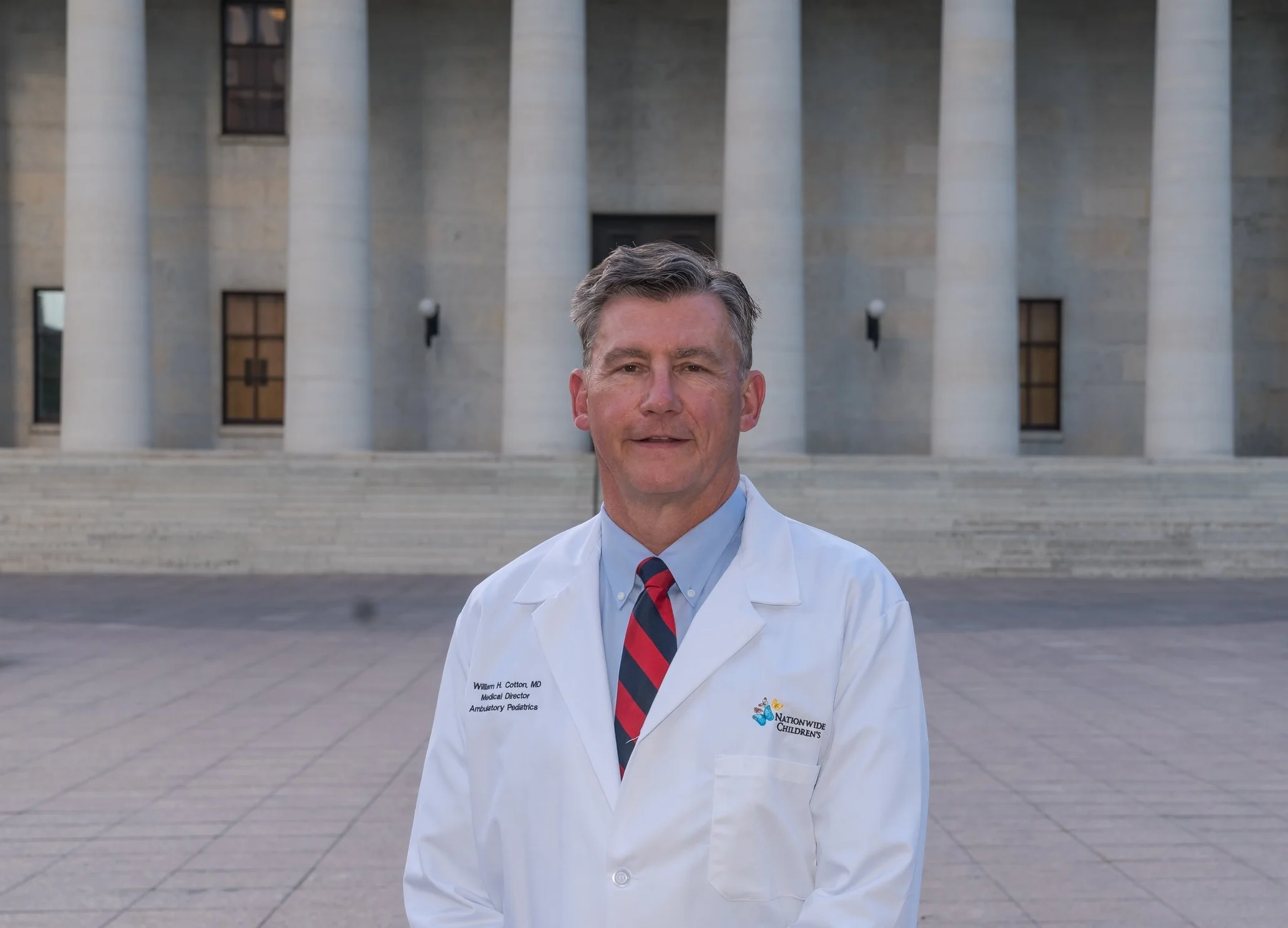 Dr. William Cotton stands in front of the Ohio Statehouse building