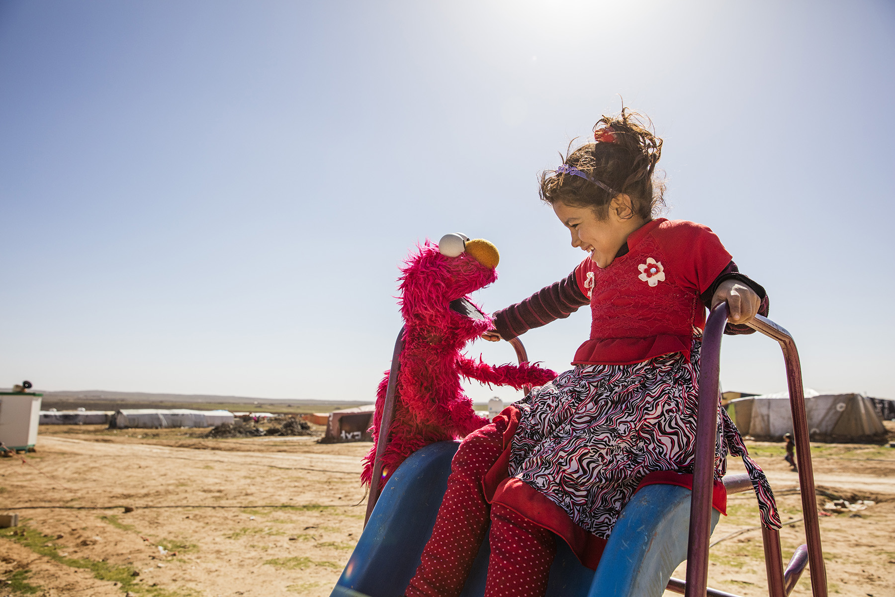 Elmo and a refugee girl in Jordan. Sesame Workshop reaches vulnerable and disadvantaged children in more than 150 countries with pre-primary education. © Sesame Workshop/Ryan Heffernan