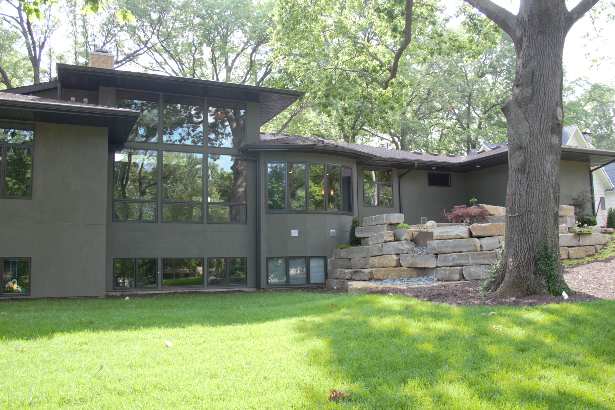 Stone retaining walls with integrated planting areas transition from the main level patio to the lower rear yard.