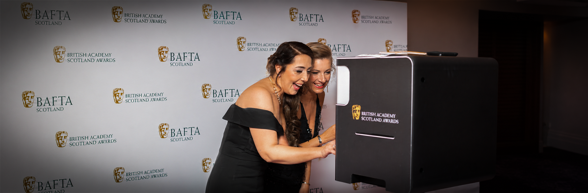 Guests in evening wear using a branded photo booth at the BAFTA Scotland Awards — photo booth hire Glasgow by Social Jungle