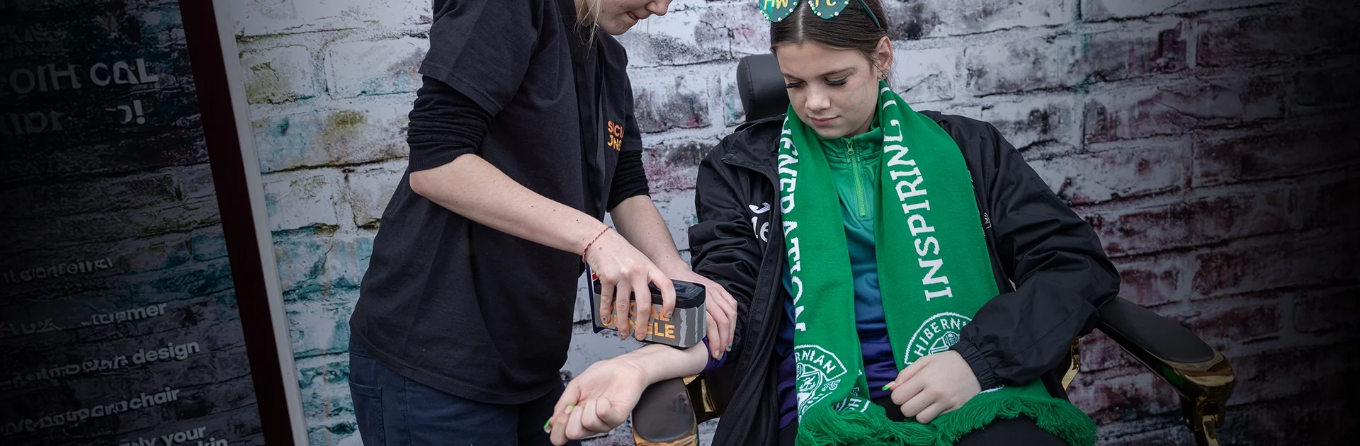 TatYou temporary tattoo activation at the SWPL Sky Sports Cup Final — Social Jungle brand ambassador applying a branded temporary tattoo to a young Hibernian FC fan