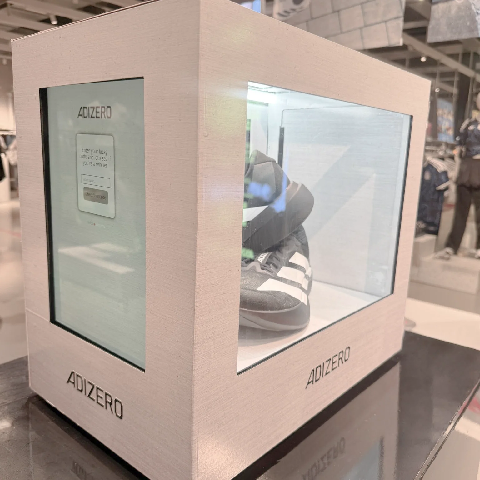 Branded ADIZERO Lockbox activation unit, with the digital keypad on one side and Adidas ADIZERO trainers visible through the clear window.