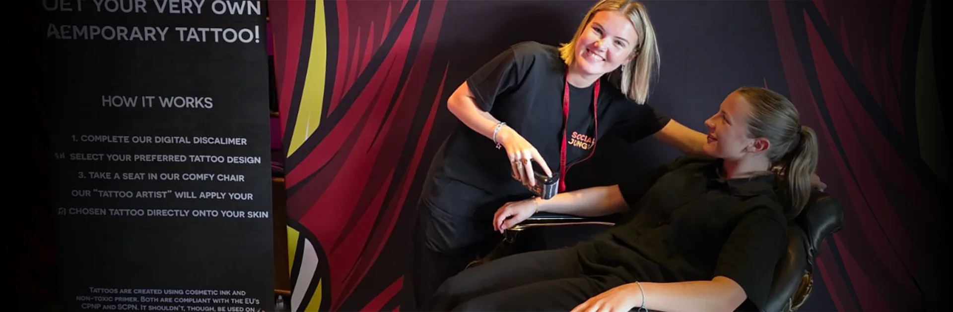 TatYou temporary tattoo activation at the Barclays Glasgow campus — Social Jungle brand ambassador applying a temporary tattoo to a guest during an ISS UK corporate event