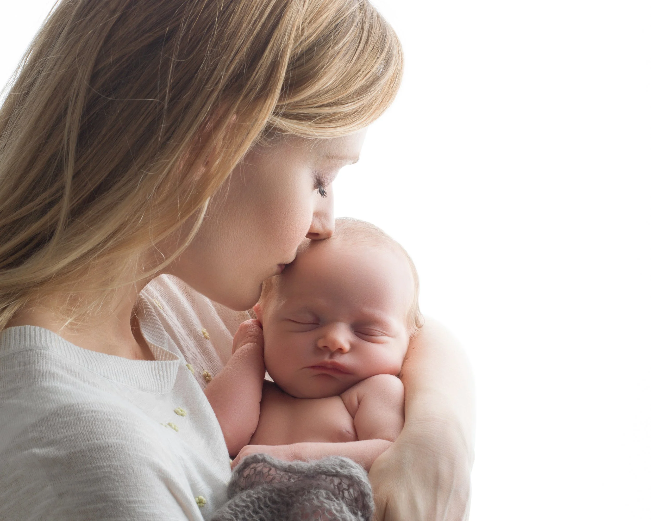Newborn photography session of a mother kissing her baby photographed by Nemi.