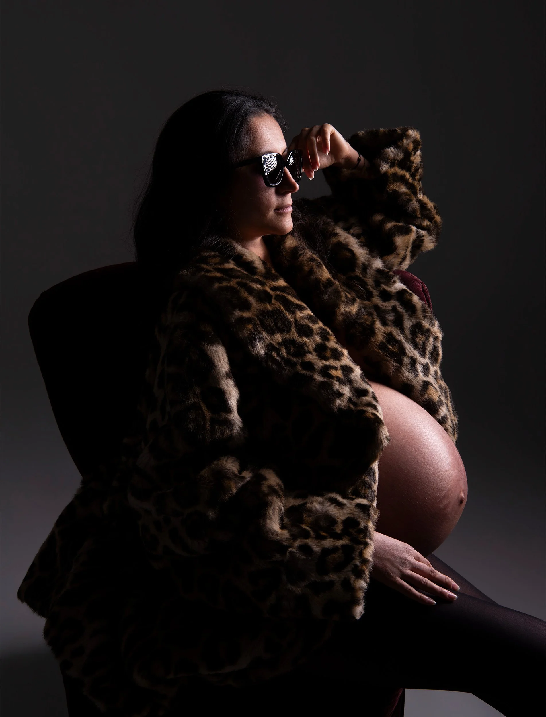 Editorial-style maternity portrait of a pregnant woman in a leopard-print coat, photographed during a fashion-inspired pregnancy photoshoot in a West London studio.