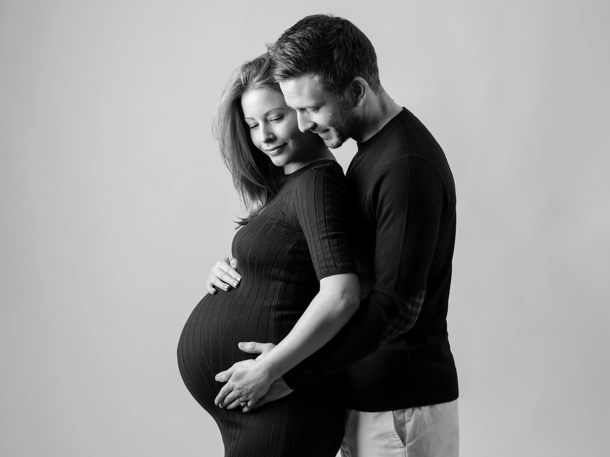 Tender maternity portrait of an expectant couple embracing during their pregnancy photoshoot in a West London studio.