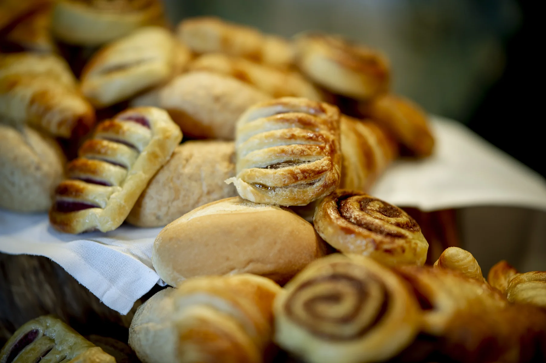 Assortment of baked pastries including cinnamon rolls, croissants, and bread rolls arranged on a platter.