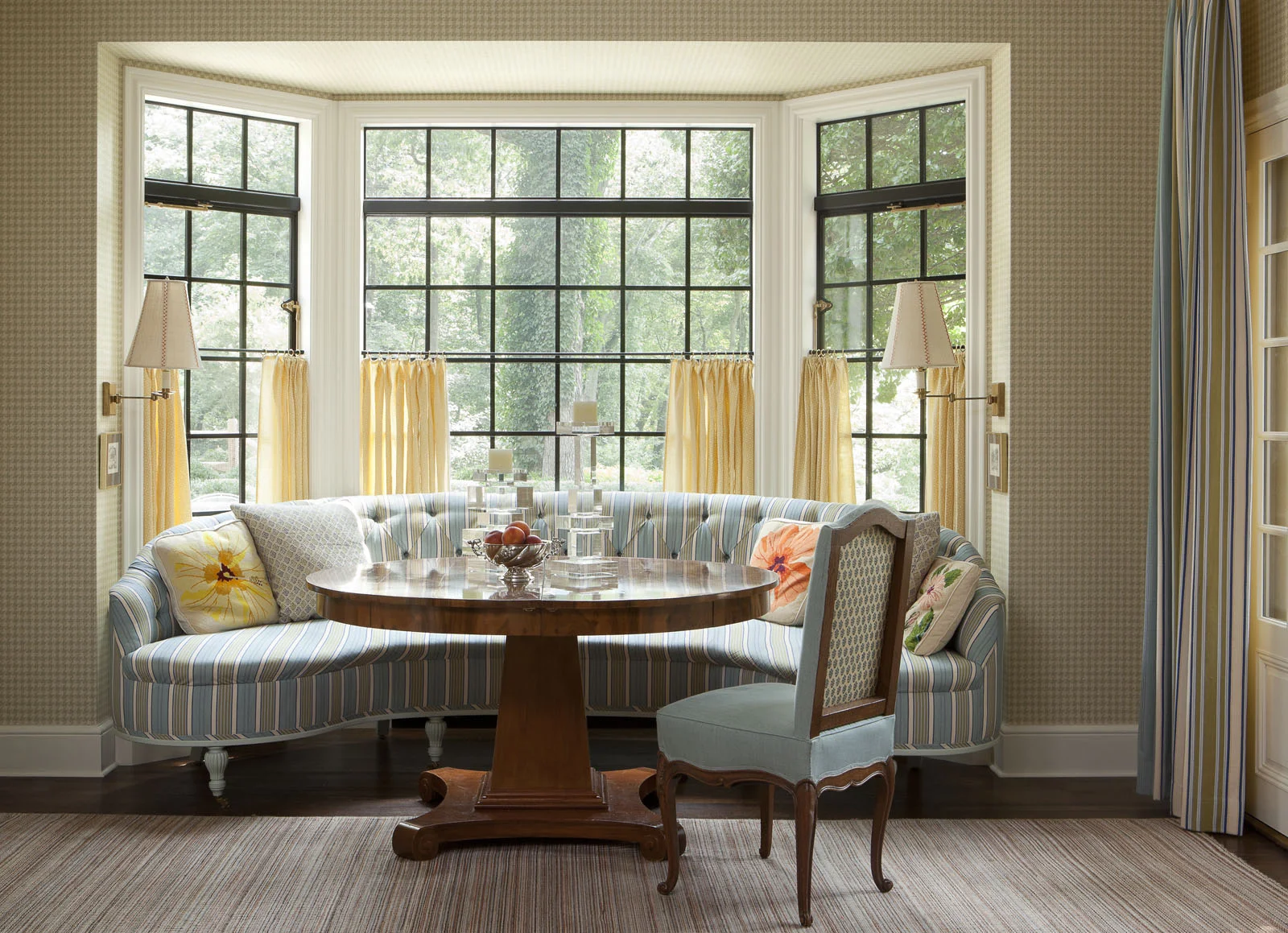 The breakfast room offers a sunny spot for casual meals. Isbell designed the banquette and dining table, the sconces are by Ann-Morris , and the wall covering is a Schumacher grass cloth.