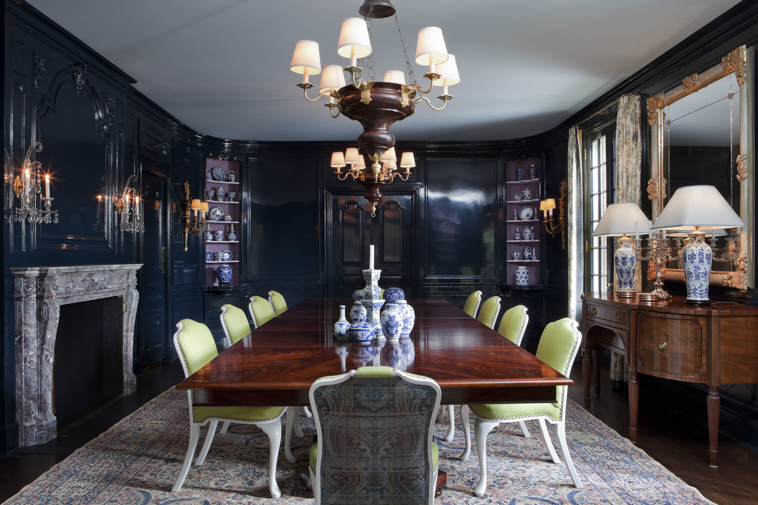  Highlighting the wife’s collection of blue-and-white porcelain was a priority in the dining room. The room’s walls are coated in a deep indigo lacquer, and the corner niches are lined in lilac burlap. To give the space versatility, Isbell designed t