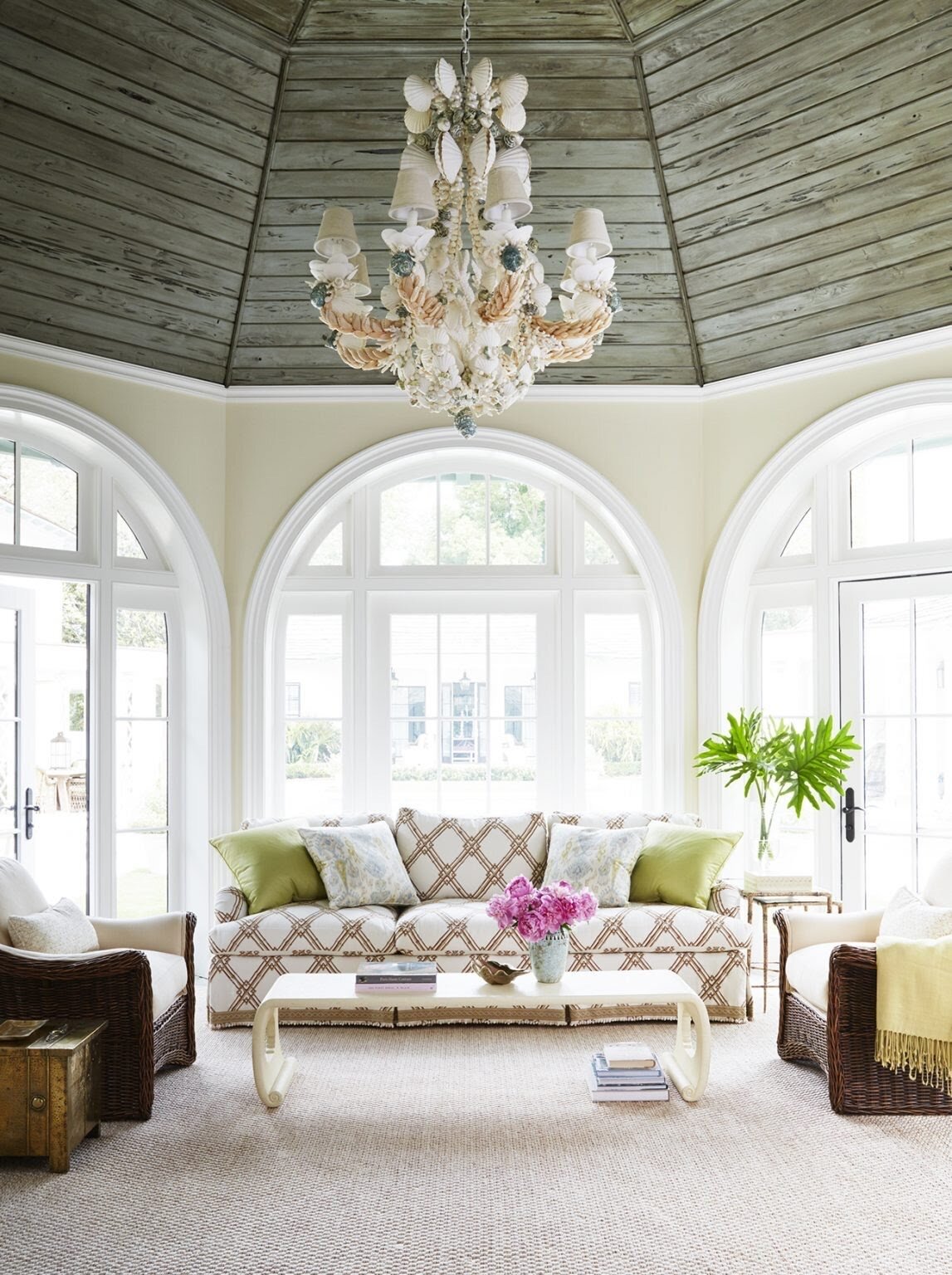  The sunroom of a home on Georgia’s Sea Island features a custom sofa, a vintage shell-encrusted chandelier and a 1960s parchment scroll table in the style of  Karl Springer  from  Horseman Antiques . Isbell says he kept the palette neutral here to e