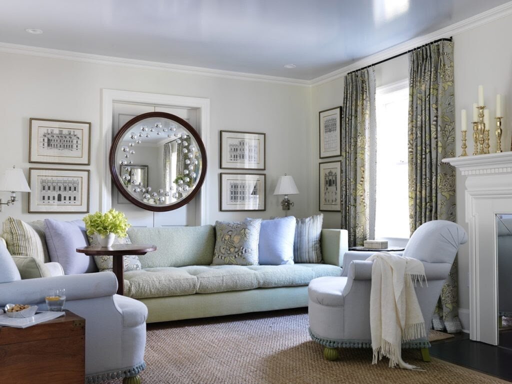  A Victorian sorcerer’s mirror holds pride of place in the living room of a home in an affluent New Jersey suburb, where it is joined by a vintage tea table from  Hamptons Antique Galleries . The custom upholstery’s pale blue and green shades create 