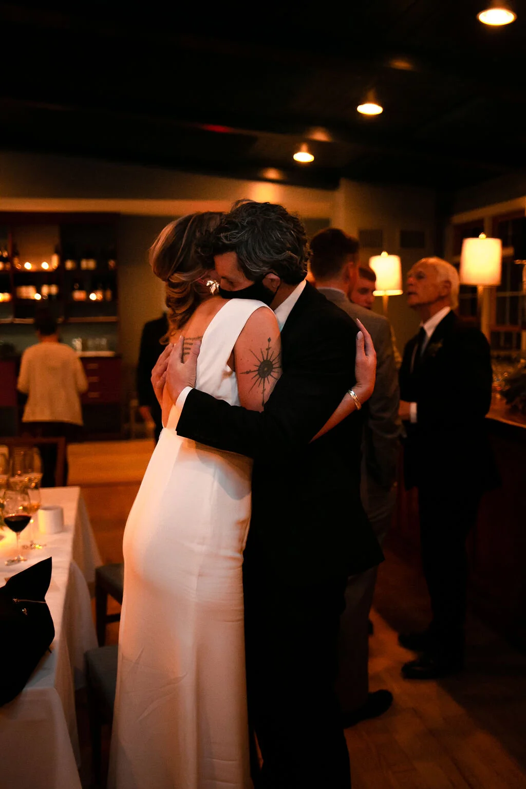 Bride and groom in masks hug at wedding reception during coronavirus pandemic