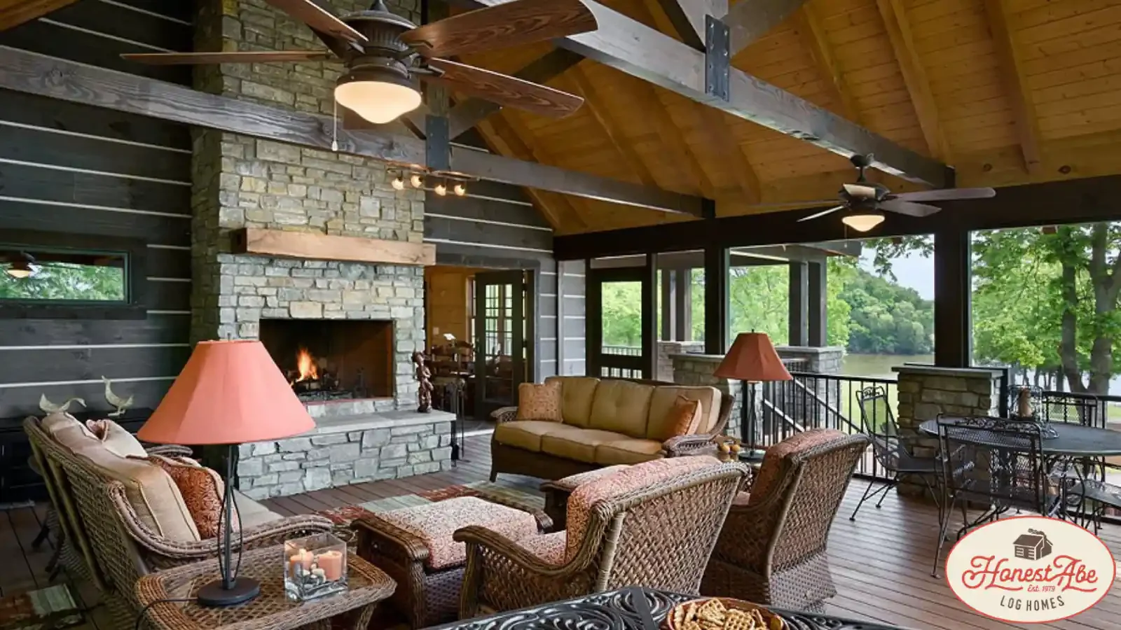 A Timber Frame Home Covered screened-in Porch with exposed header beams, multiple ceiling fans, stone exterior fireplace, wicker and wrought iron furniture, lake side with up to 100% construction loan from BuildBuyRefi.com