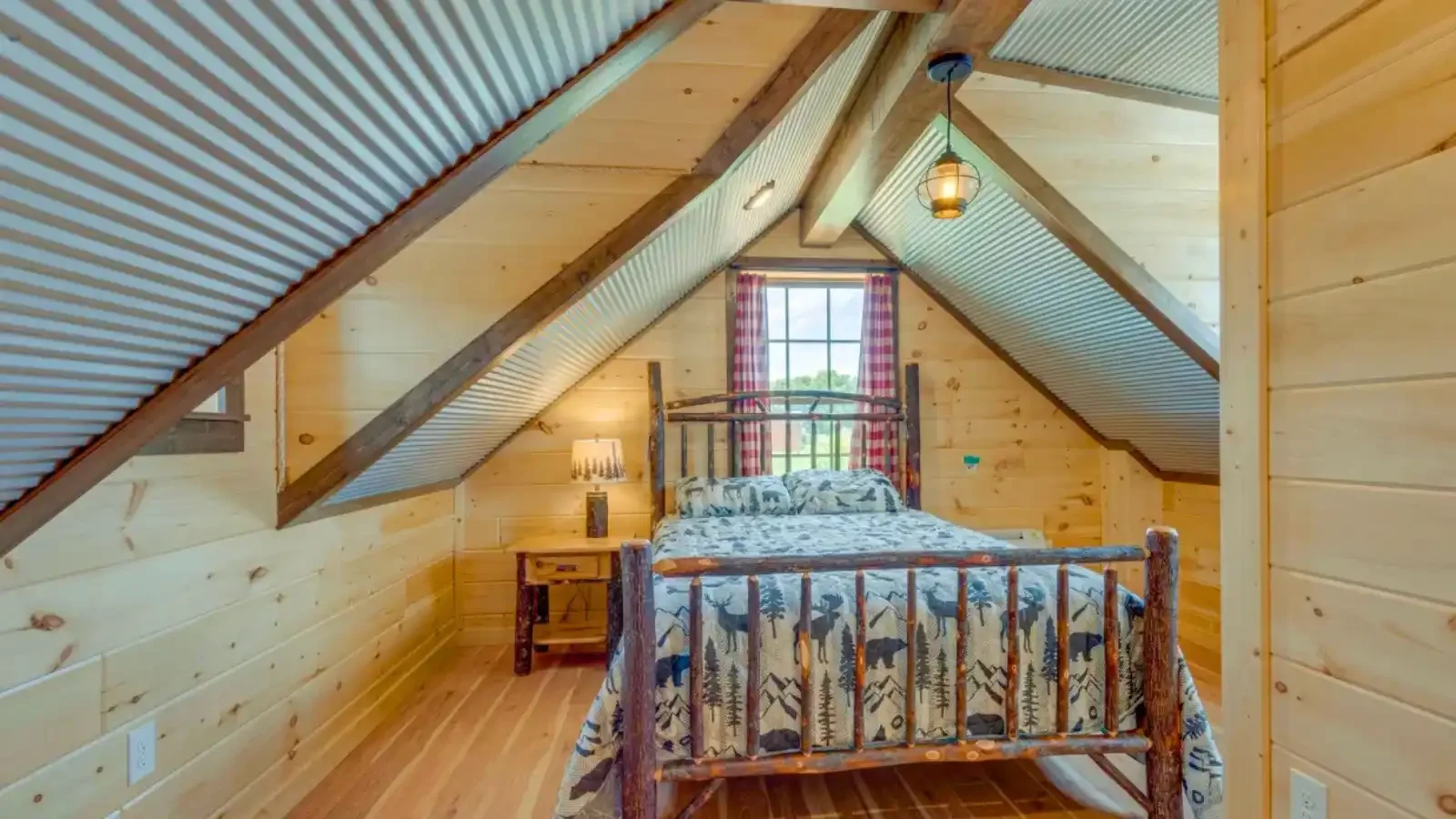 The Yellowstone interior upstairs bedroom with front and rear dormer windows and vaulted ceilings with queen size bed and ensuite bathroom by Amish Built Cabins and financing by BuildBuyRefi Home Loans.