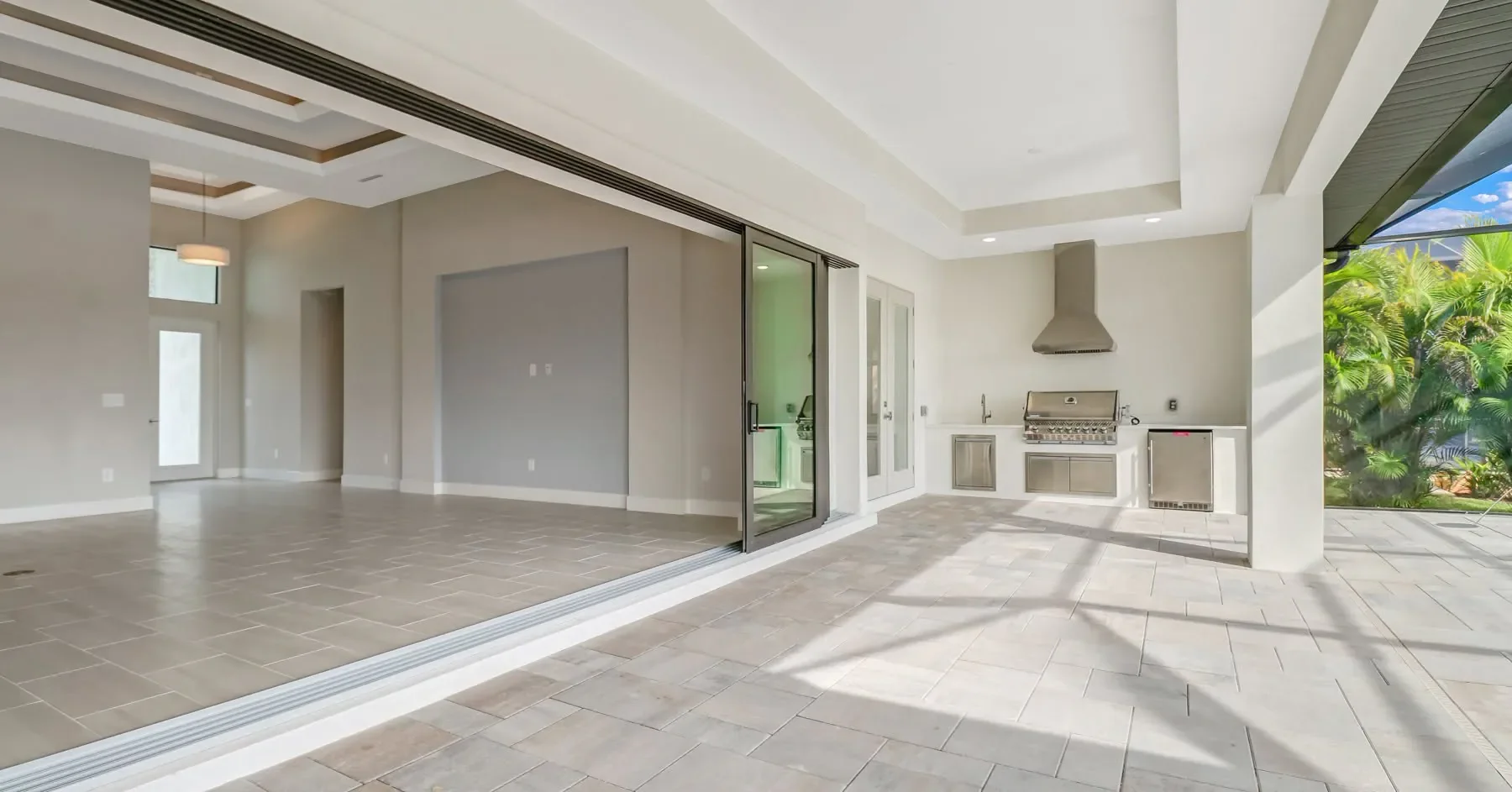 Gorgeous expansive back covered porch, full wall of sliding windows to outside kitchen, and pool areas, custom tray ceilings, fully custom tile and patio stone designed by by Sposen Signature Homes of Florida and BuildBuyRefi.com