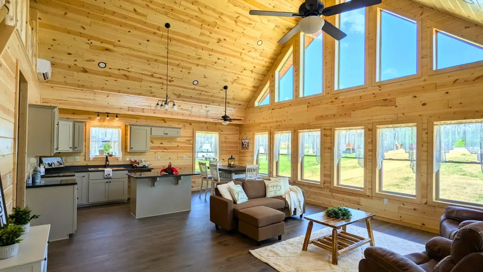 Beautiful open floor plan with Vaulted 2-Story windows of living, dining, and kitchen with island by Amish Built Cabins, offered with up to 100% land and home loans for log cabins by BuildBuyRefi.com