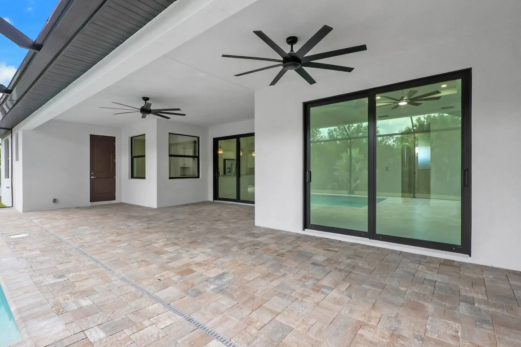 Unique outdoor covered back patio into the screened in pool area, dual fans, stone walk area, multiple double door sliders, custom built by Sposen Signature Homes of Florida & BuildBuyRefi.com