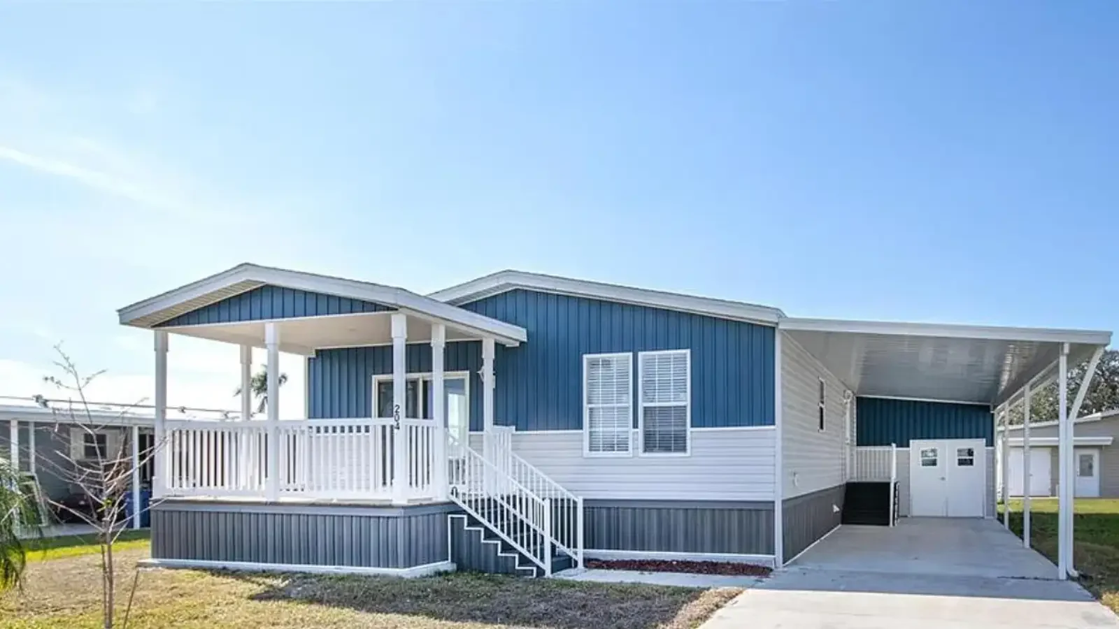 Gorgeous Suncrest Homes Manufactured doublewide with covered porch deck, large carport, double door john deere storage garage, multi tone siding, all custom, and up to 100% financing from BuildBuyRefi Home Loans.